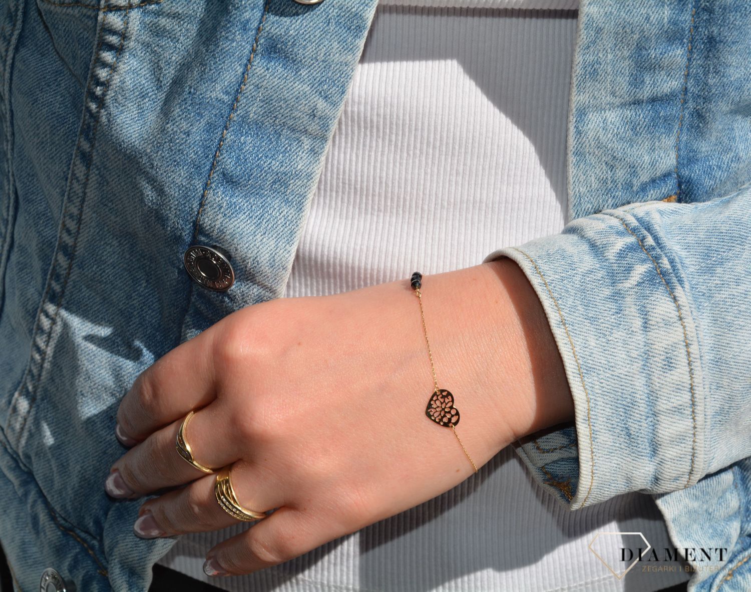 Złota bransoletka celebrytka na delikatnym łańcuszku ozdobiona została zawieszką w kształcie ażurkowego serca oraz trzech czarnych koralików. Zapraszamy!  (1).jpg