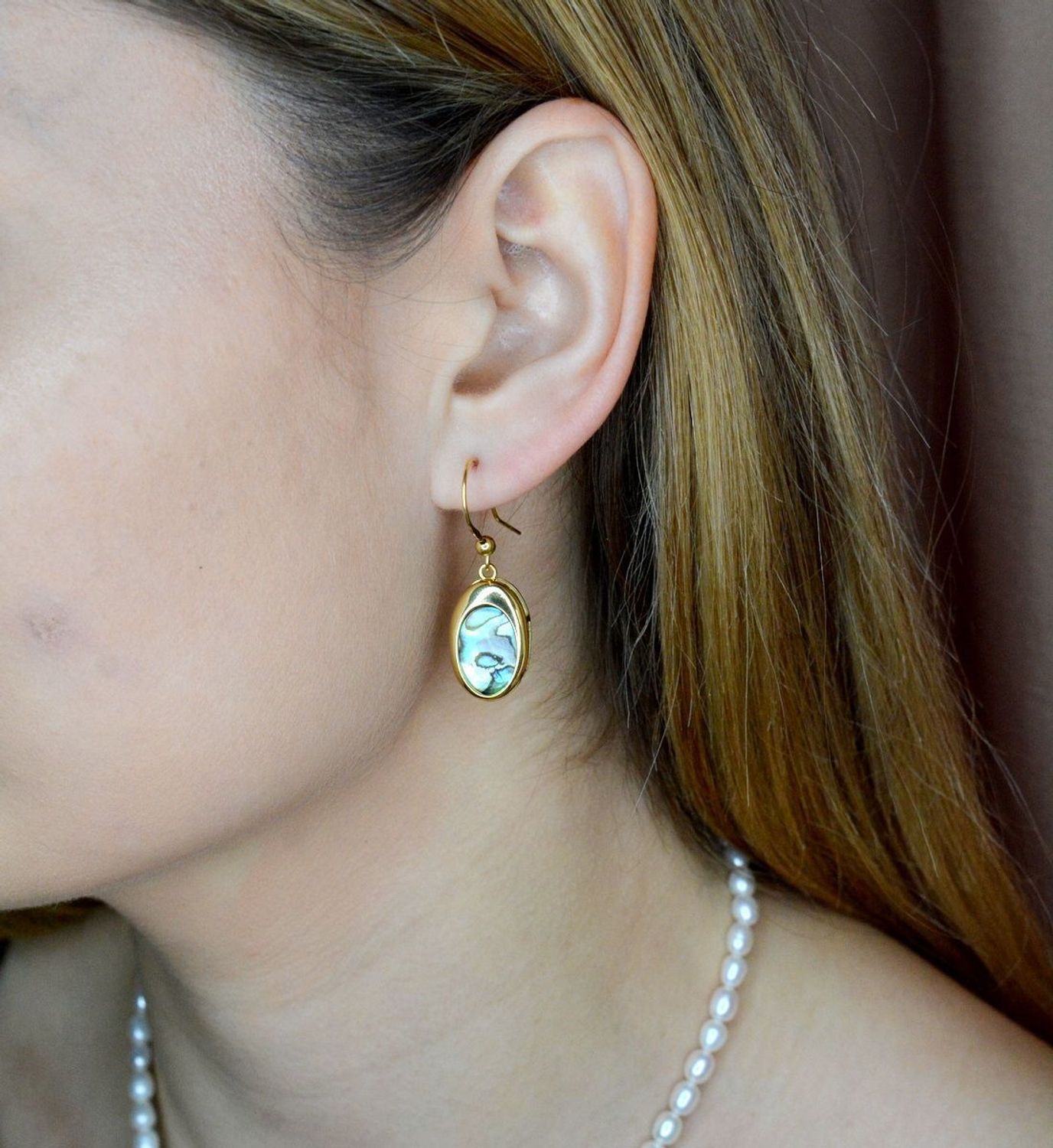 Srebrne kolczyki wiszące pokryte złotem z muszlą naturalną 0714858290. Kolczyki o owalnym kształcie z muszlą naturalną to doskonała propozycja dla osób szukających modnych, minimalistycznych dodatków. Kolczyki z wygodnym zapięciem na.jpg