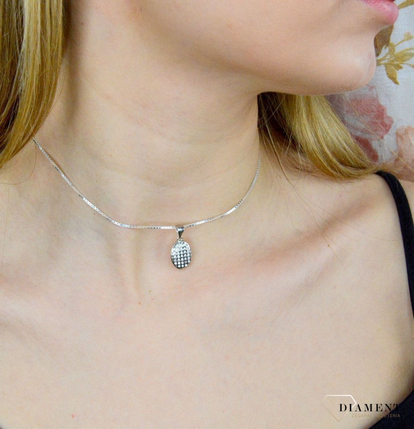 Srebrna zawieszka o owalnym kształcie wysadzona cyrkoniami AZZ000000-275. Drobna zawieszka wysadzana cyrkoniami stanowi piękną ozdobę dekoltu. Subtelna, a jednocześnie elegancka zawieszka sprawdzi się idealnie na prezen.jpg