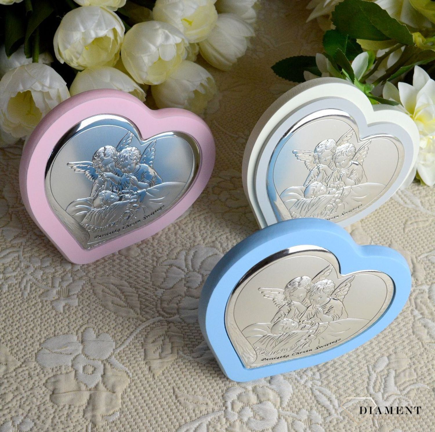 Uroczy obrazek w kształcie serca z wizerunkiem dwóch aniołków pochylających się nad dzieckiem. Wykonany z wysokiej jakości drewna oraz metalu laminowanego srebrem, dzięki któremu produkt zachowa swój blask.webp