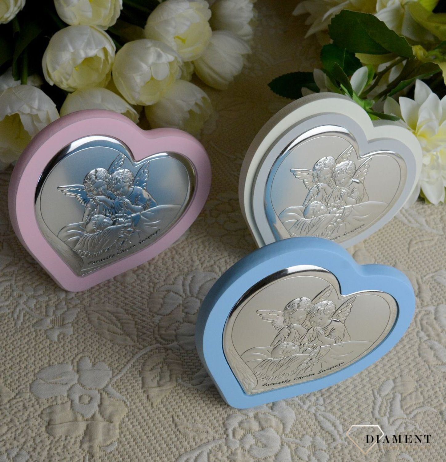 Uroczy obrazek w kształcie serca z wizerunkiem dwóch aniołków pochylających się nad dzieckiem. Wykonany z wysokiej jakości drewna oraz metalu laminowanego srebrem, dzięki któremu produkt zachowa swój blask.webp