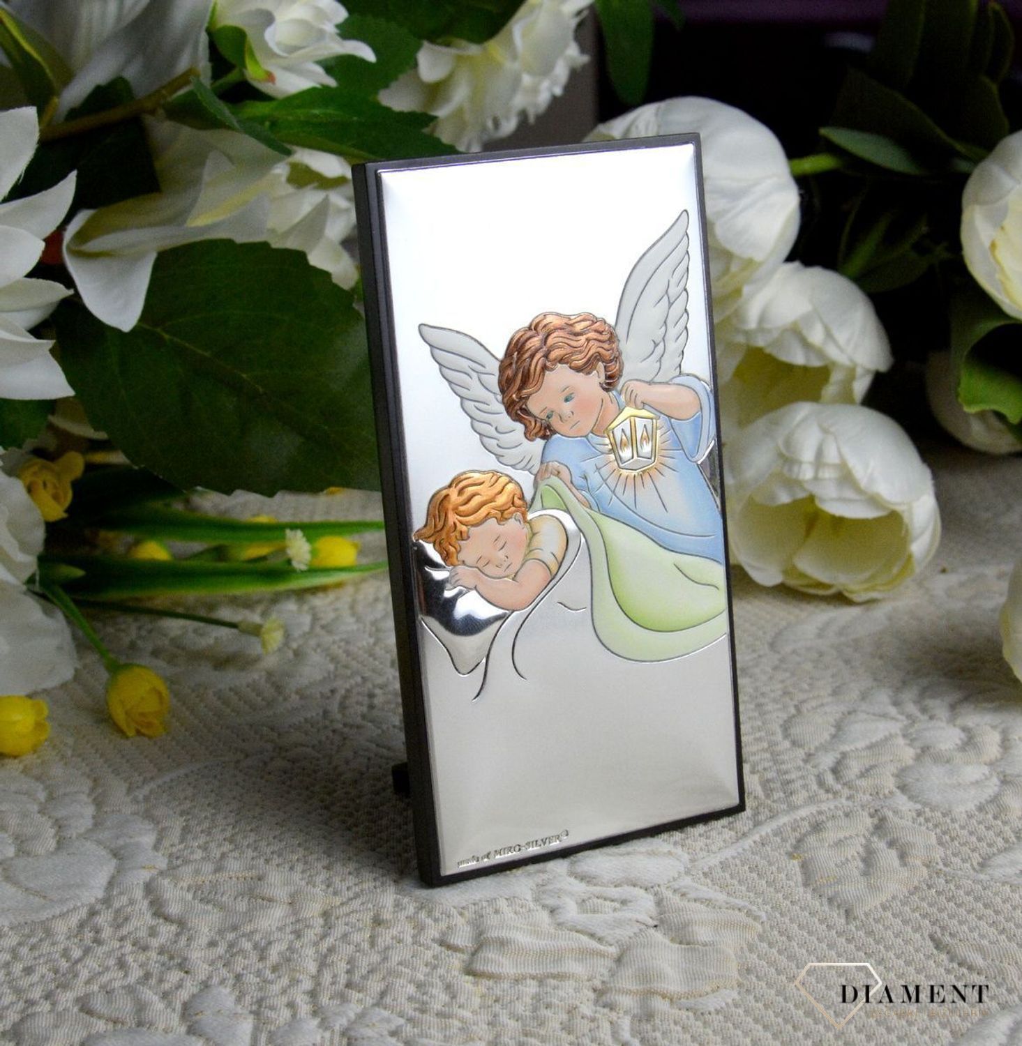 Obrazek srebrny z Aniołem Stróżem to piękna ozdoba dziecięcego pokoju. Pamiątka jest symbolicznym przedstawieniem opieki roztoczonej nad malcem przez Bożą Opatrzność..webp