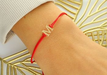 Subtelna bransoletka damska ze złota próby 585 na czerwonym sznureczku z literką „M”. Ściągane zapięcie, regulowana długość, idealna na prezent lub jako osobisty talizman.2.jpg