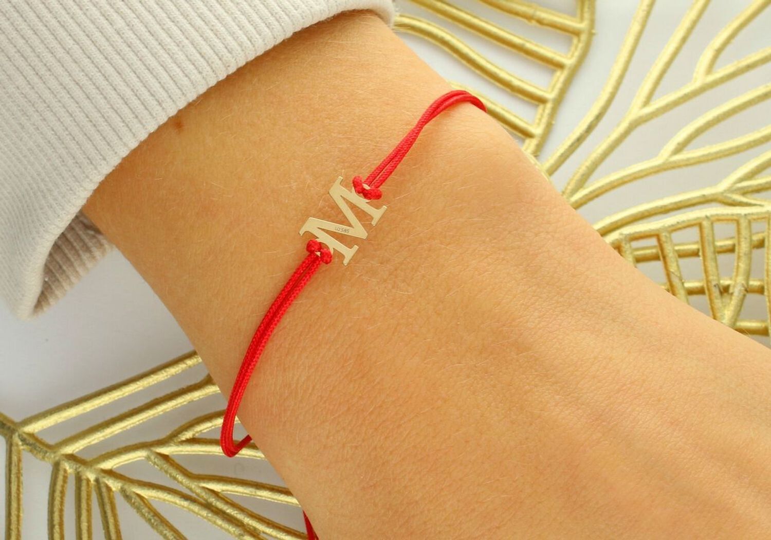 Subtelna bransoletka damska ze złota próby 585 na czerwonym sznureczku z literką „M”. Ściągane zapięcie, regulowana długość, idealna na prezent lub jako osobisty talizman.1.jpg
