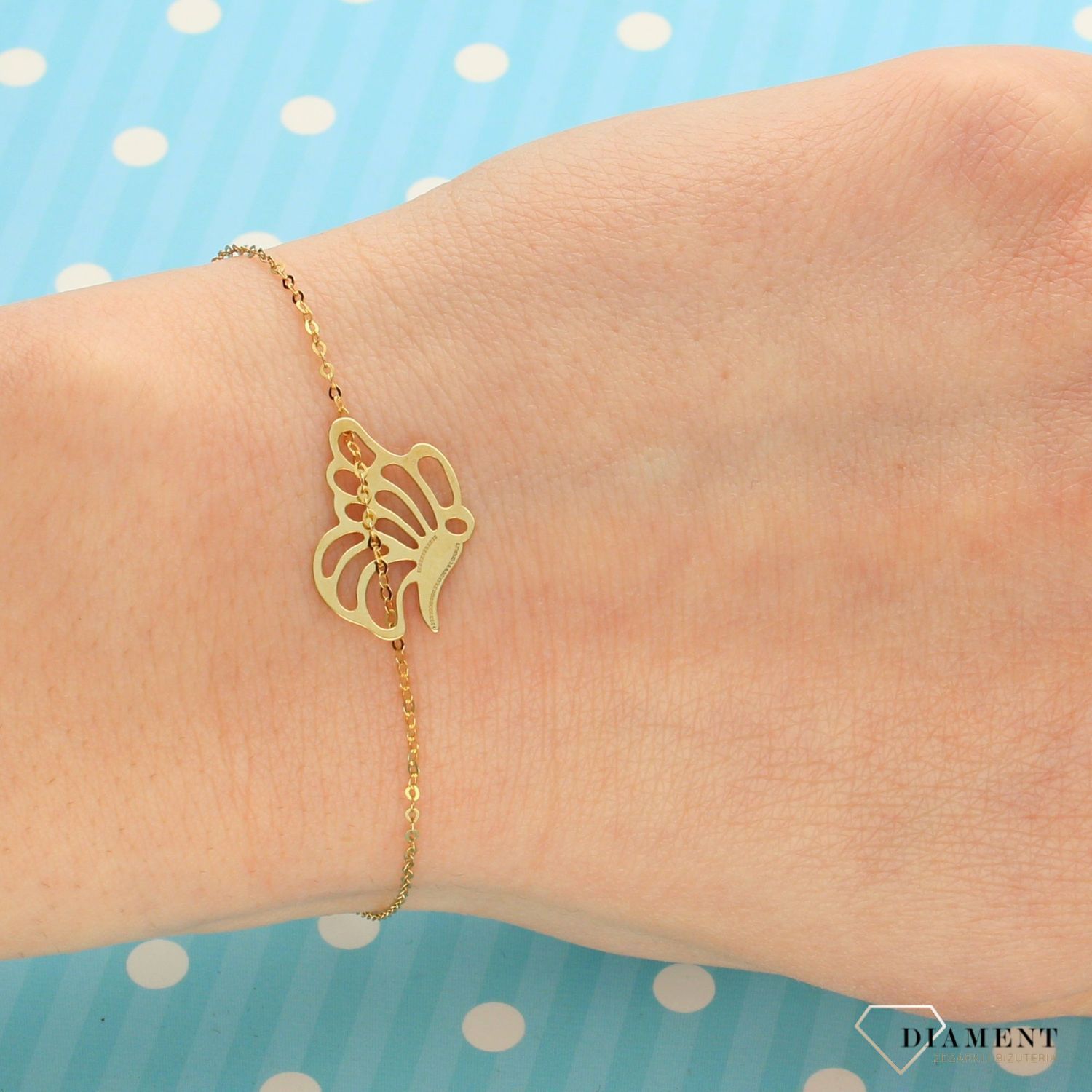 Złota bransoletka typu celebrytka z ozdobnym elementem w postaci motyla. Bransoletka składa się z drobnego, ażurkowego łańcuszka. Bransoletka z przedłużką.  (2).jpg