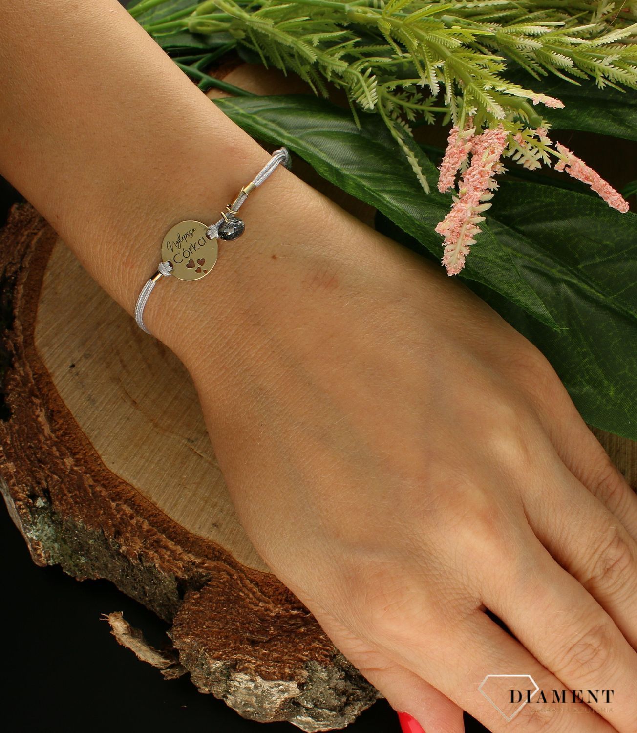 Bransoletka na sznureczku ze srebrną-pozłacaną zawieszką w okrągłym kształcie z napisem Najlepsza Córka. Piękny prezent na pewno sprawi radość ukochanej babci.png