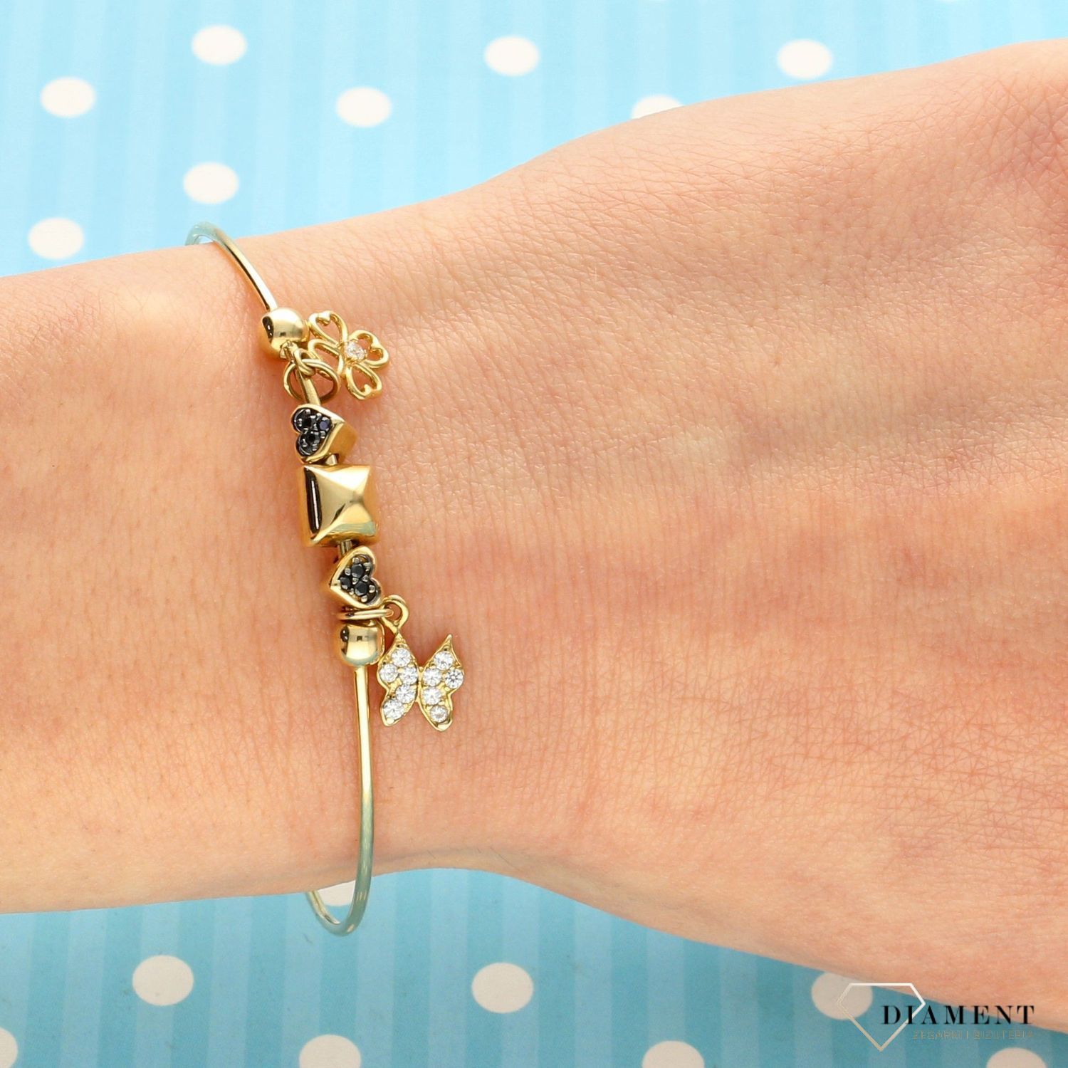 Złota, sztywna bransoletka z elementami ozdobnymi w postaci motylka i koniczynki. Bransoletka wykonana z wysokiej jakości złota próby 585. Zapraszamy!  (1).jpg