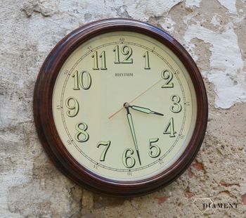 Zegar ścienny do salonu Rhythm CMG856NR06 to ozdobny, prosty zegar pasujący do każdego wnętrza. Ciekawa stylizacja zegara w kolorze brązowym. Wymarzony prezent (1).JPG