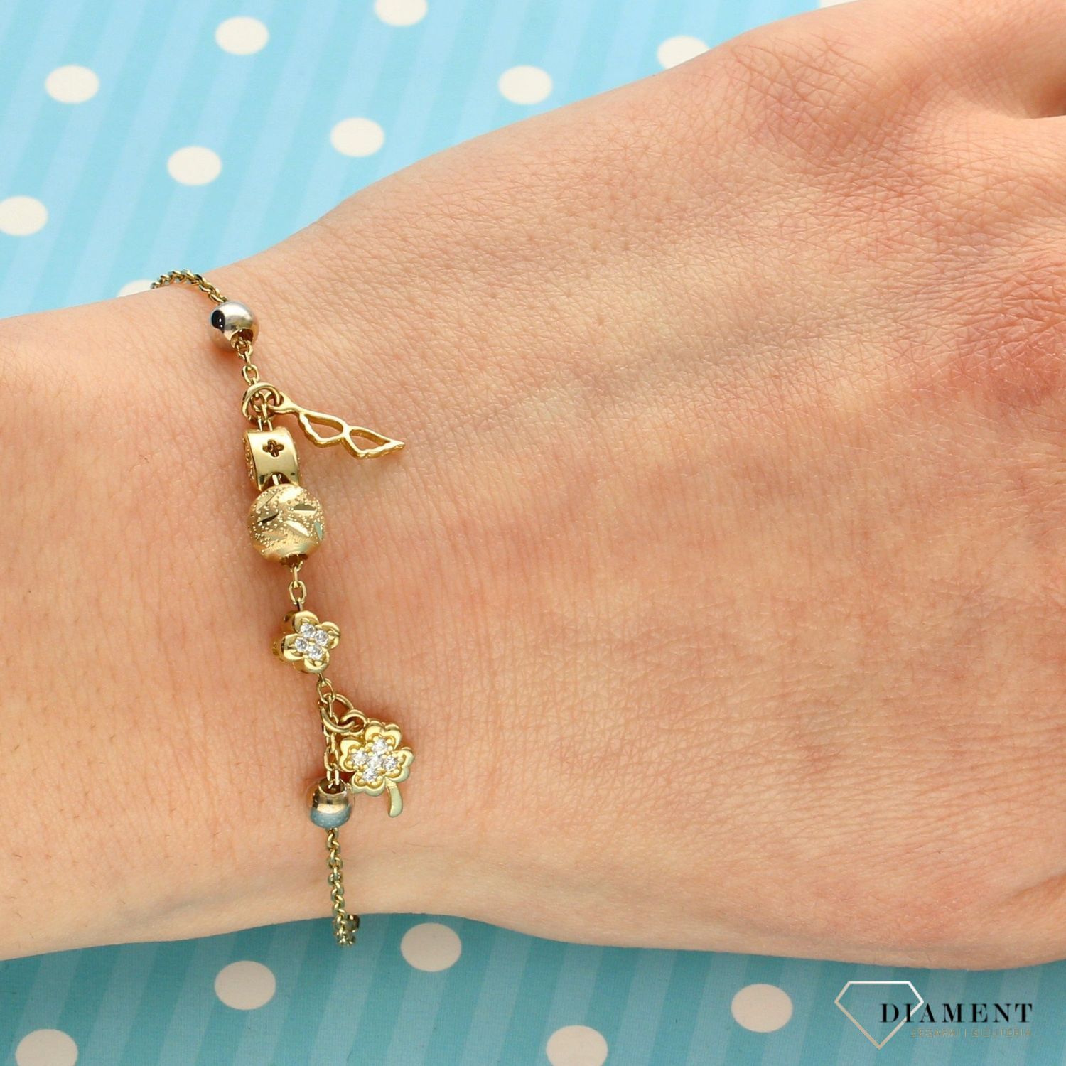 Złota bransoletka celebrytka z zawieszkami koniczynką i skrzydełkami. Złota bransoletka w kolorze żółtego złota wykonana z próby 585. Zapraszamy!  (1).jpg