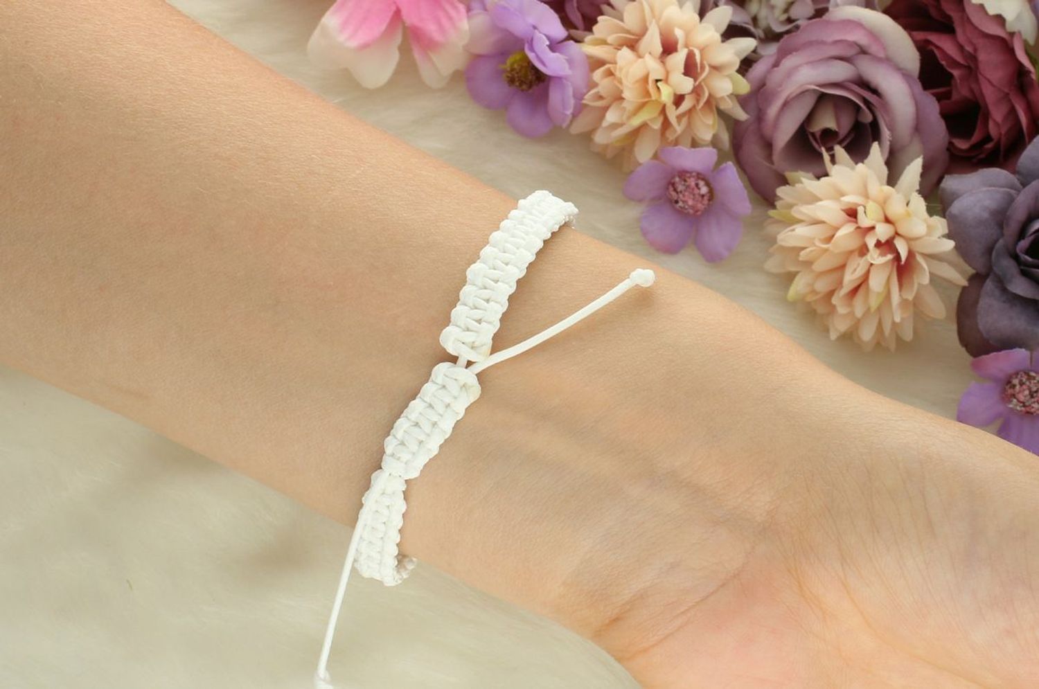 Delikatna srebrna bransoletka 925 z wiszącą zawieszką w kształcie kwiatków na białym sznurku. Regulowane zapięcie, subtelny design – idealna na prezent lub na co dzień.1.jpg