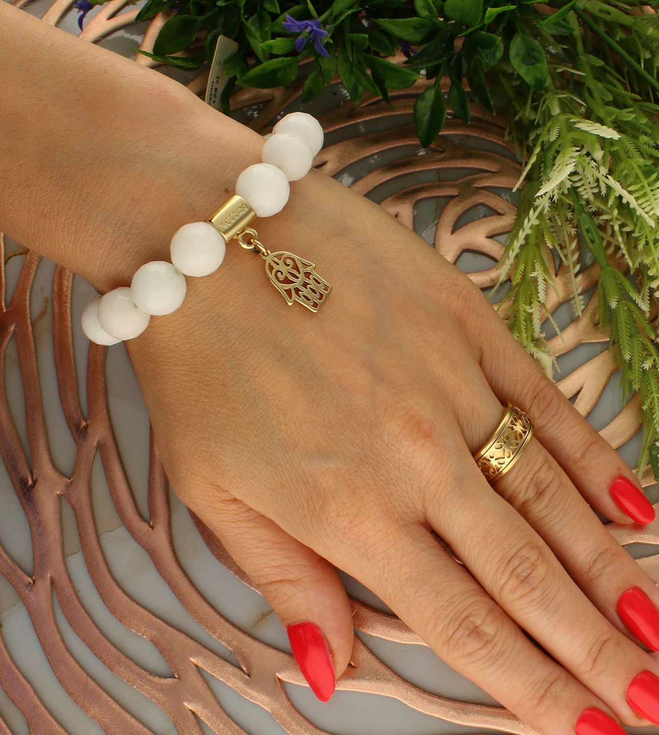 Bransoletka damska na gumce mleczne koraliki z pozłoconą ręką fatimy DIA-BRA-5671-INNE.  Bransoletka na gumce to biżuteria cechująca się one oryginalnością i wygodą, która zachwyci każdą kobietę. Oryginalny  pomysł na prezen.jpg