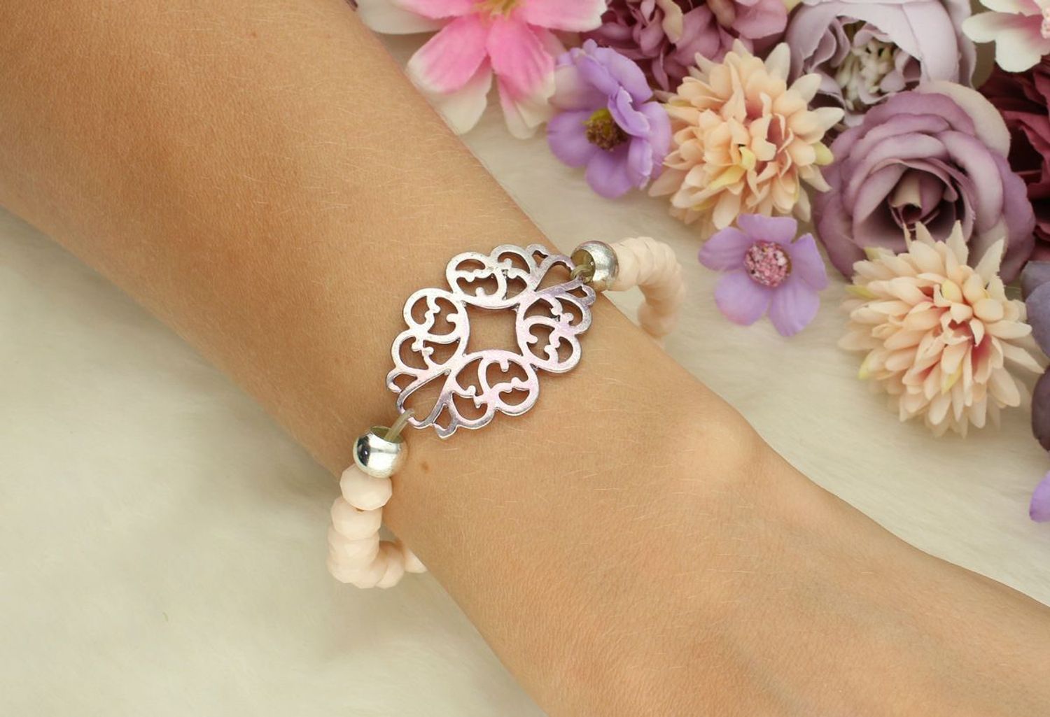 Bransoletka damska elastyczna DIA-BRA-6131-MET z beżowymi kamieniami i ażurową zawieszką 3,5x2,5 cm. Wygodna, kobieca, idealna na prezent i do codziennych stylizacji.1.jpg