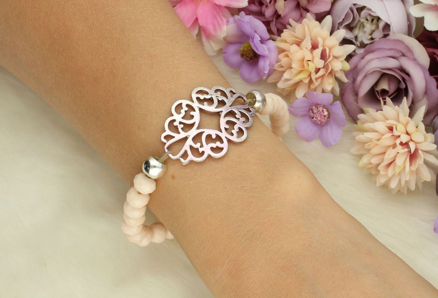 Bransoletka damska elastyczna DIA-BRA-6131-MET z beżowymi kamieniami i ażurową zawieszką 3,5x2,5 cm. Wygodna, kobieca, idealna na prezent i do codziennych stylizacji.1.jpg