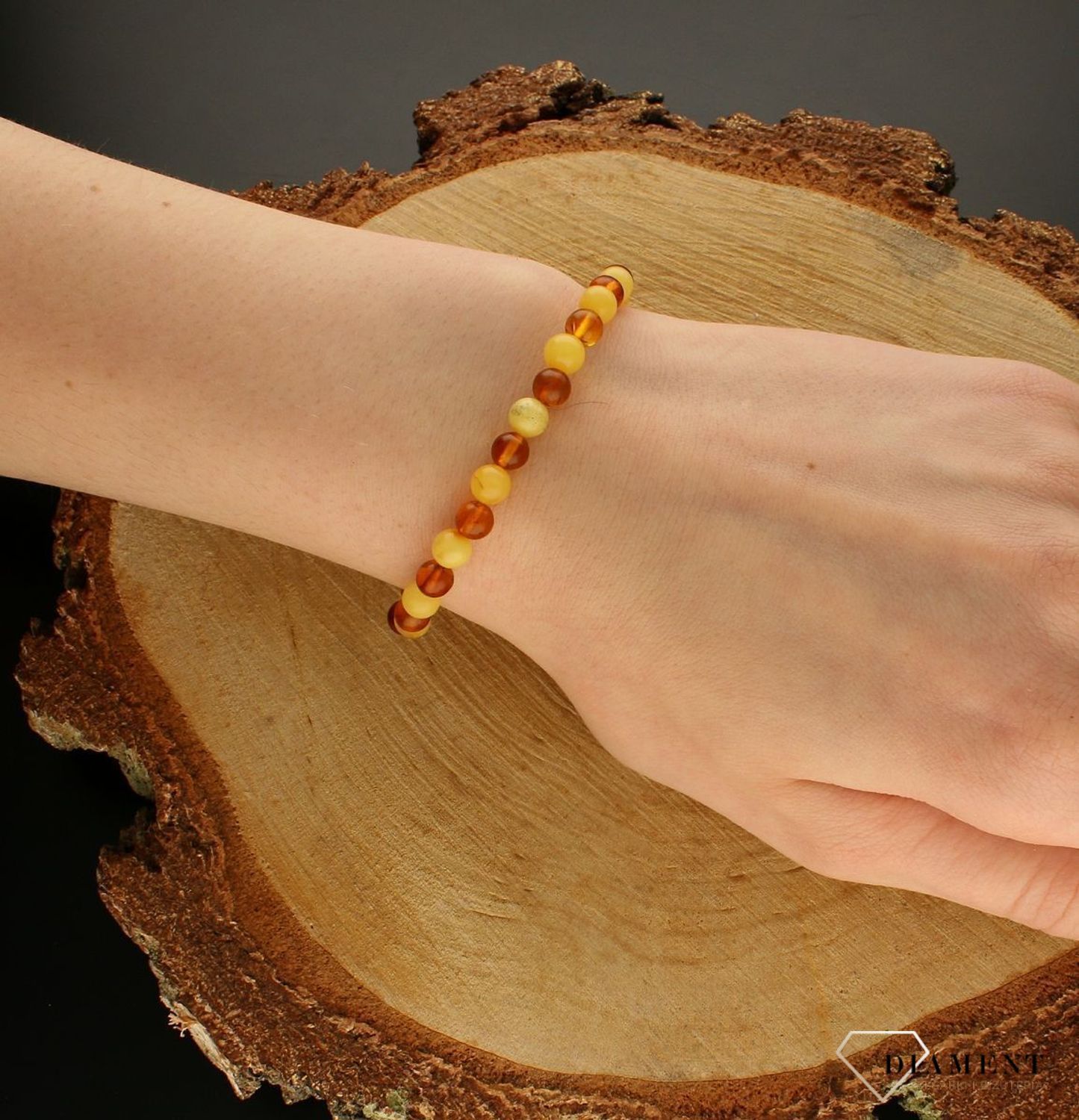Bransoletka damska na gumce z brązowym i żółtym bursztynem DIA-BRA-9845-BURSZTYN.  Bursztyn to propozycja od sklepu jubilerskiego Diament.  Bransoletka z bursztynu będzie ciekawą ozdobą dla wielu kreacji jak również idealnym pomysł (3).jpg