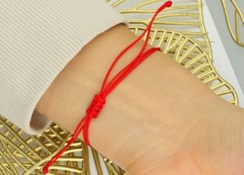 Subtelna bransoletka damska ze złota próby 585 na czerwonym sznurku z okrągłą zawieszką symbolem zodiaku Ryby. Ściągane zapięcie, regulowana długość, idealna na prezent lub osobisty talizman.3.jpg
