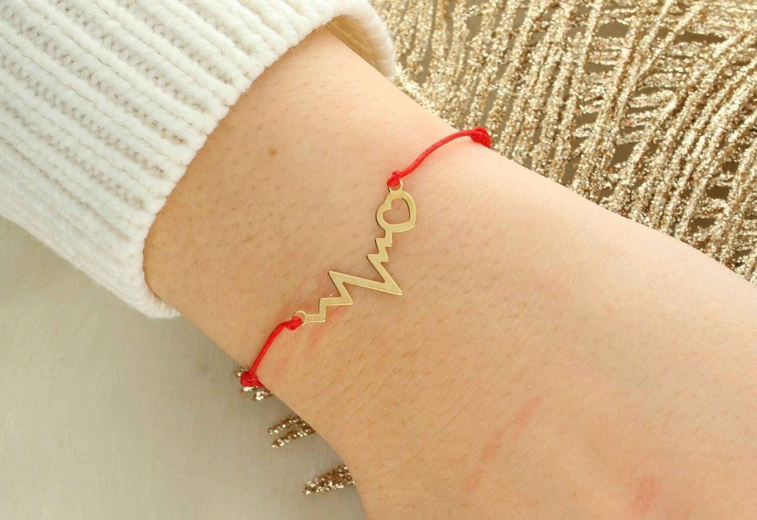 Bransoletka na czerwonym sznurku jubilerskim ze złotem próby 585. Motyw EKG z sercem (10x25 mm), blaszka 5x7 mm, regulowana długość. Waga złota 0,60 g. Symboliczna, lekka, idealna na prezent.1.jpg