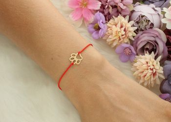 Złota bransoletka damska próby 585 z czerwoną nitką i zawieszką w kształcie psiej łapki (1,1 cm). Regulowane zapięcie, waga 0,44 g. Model DIA-BRA-LU104G14KRED – subtelna i symboliczna.2.jpg
