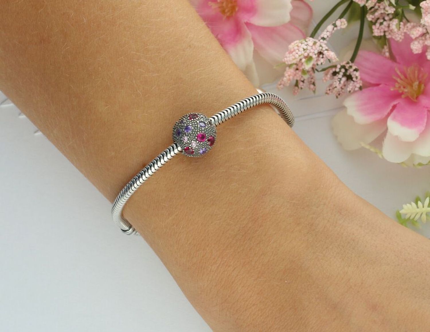 Okrągły charms srebrny próby 925 w formie klipsa, zdobiony różowo-fioletową cyrkonią. Kobiecy i elegancki dodatek do bransoletki. Waga 3,80 g, wielkość 1,0 cm.1.jpg