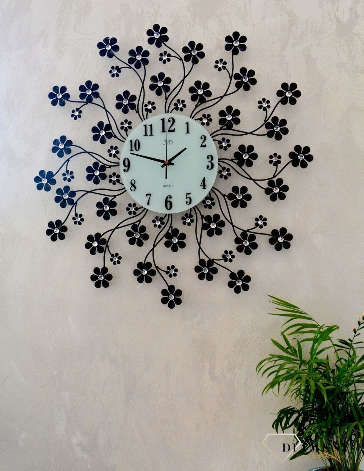Zegar na ścianę nowoczesny z kryształkami JVD kwiatki HJ85.  Zegar ścienny JVD HJ85 wyposażony jest w kwarcowy mechanizm, zasilany za pomocą baterii. Posiada bardzo wysoką dokładność mierzenia czasu +- 10 sekund w przeciągu 30 dni..jpg