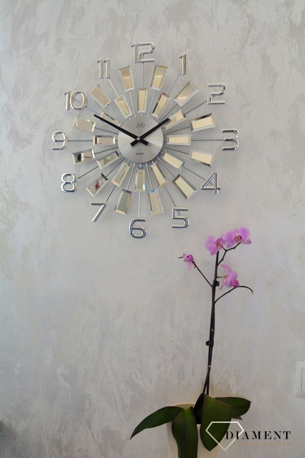 Zegar ścienny 49 cm z kryształkami Cristal JVD HT100.3 wyposażony jest w kwarcowy mechanizm, zasilany za pomocą baterii. Posiada bardzo wysoką dokładność mierzenia czasu +- 10 sekund w przeciągu 30 dni..webp