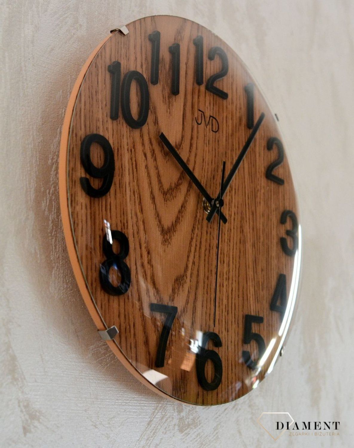 Zegar na ścianę drewniany JVD 30 cm HT98.7. Ścienny zegar JVD HT98.7 wyposażony jest w kwarcowy mechanizm, zasilany za pomocą baterii. Posiada bardzo wysoką dokładność mierzenia czasu +- 10 sekund w przeciągu 30 dni..jpg