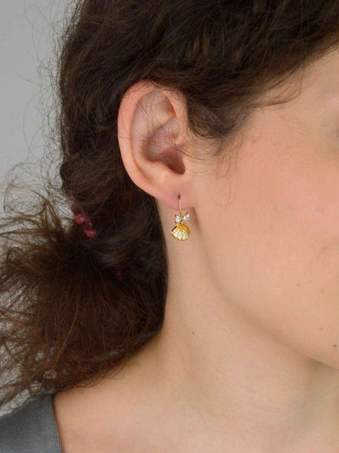 Eleganckie kolczyki damskie srebrne pozłacane próby 925 – model DIA-KLC-13655-925. Wiszące muszelki z białą perłą i kokardką z cyrkonii. Zapięcie bigiel otwarty. Lekkie, subtelne – idealne na pr.jpg