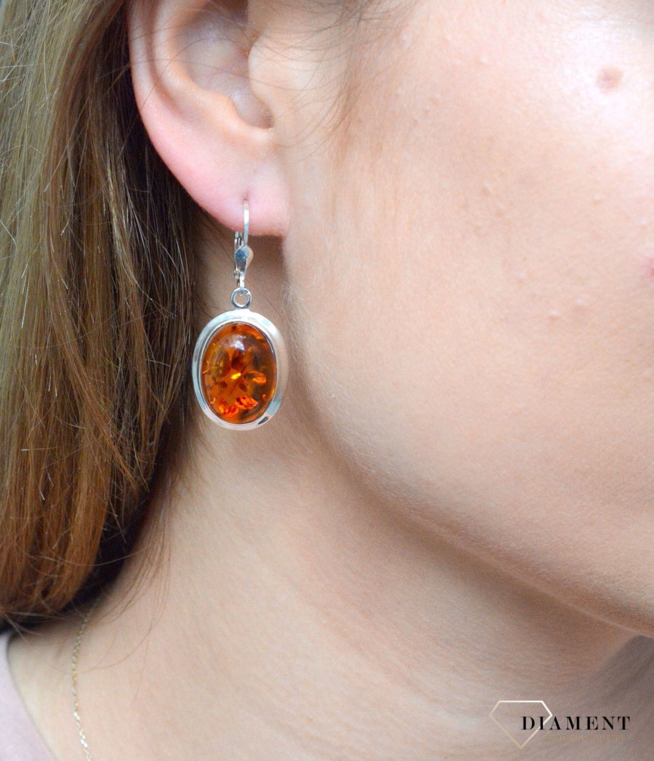 Kolczyki srebrne wiszące z owalnym bursztynem DIA-KLC-7079-925. Srebrne kolczyki z bursztynem to modelem bardzo ciekawy, ponieważ dzięki ciepłej kolorystyce pięknie podkreśla on urodę. Charakteryzują się stylem wiszącym i zaw.jpg