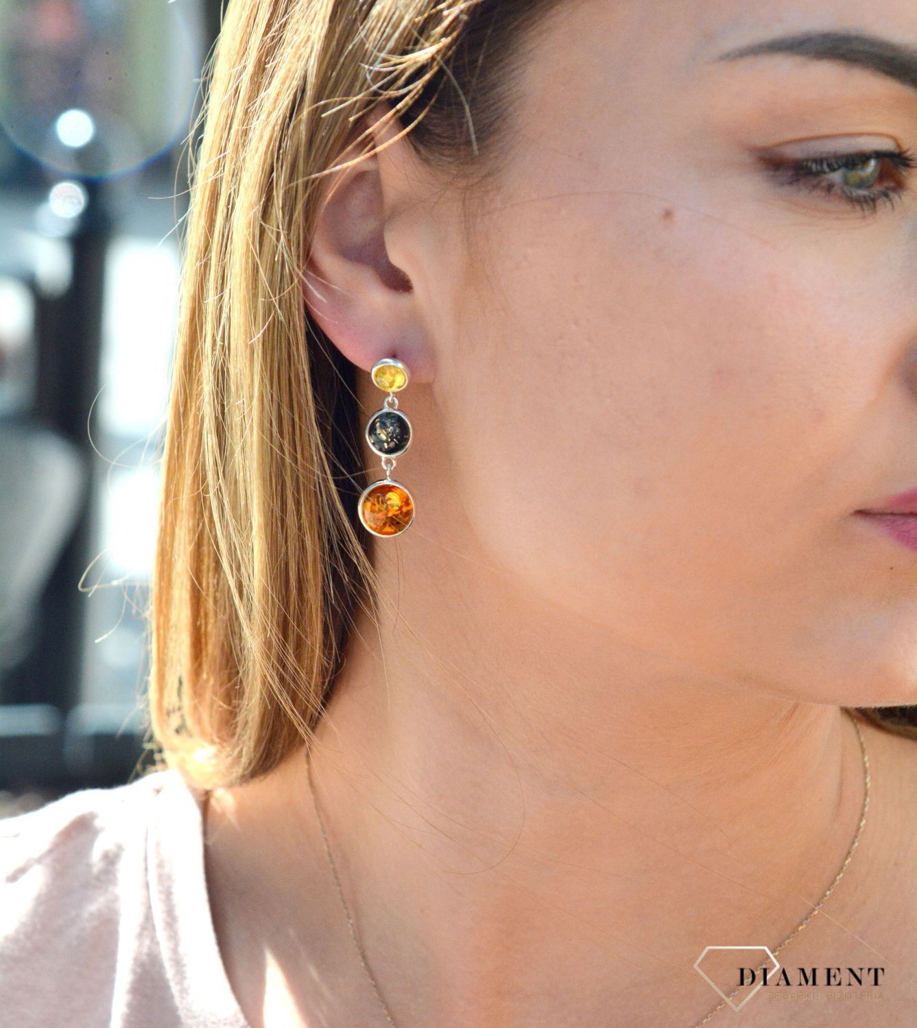 Kolczyki srebrne wiszące z kolorowymi bursztynami DIA-KLC-7096-925. Charakteryzują się stylem klasycznym i zapięciem na wygodny sztyft. Oprawa elementu ozdobnego, wykonana ze srebra, ma efektowny kształt. Bursztyn to słoneczny.jpg