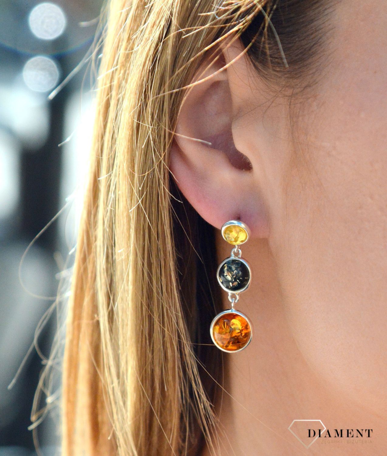 Kolczyki srebrne wiszące z kolorowymi bursztynami DIA-KLC-7096-925. Charakteryzują się stylem klasycznym i zapięciem na wygodny sztyft. Oprawa elementu ozdobnego, wykonana ze srebra, ma efektowny kształt. Bursztyn to słoneczny.jpg