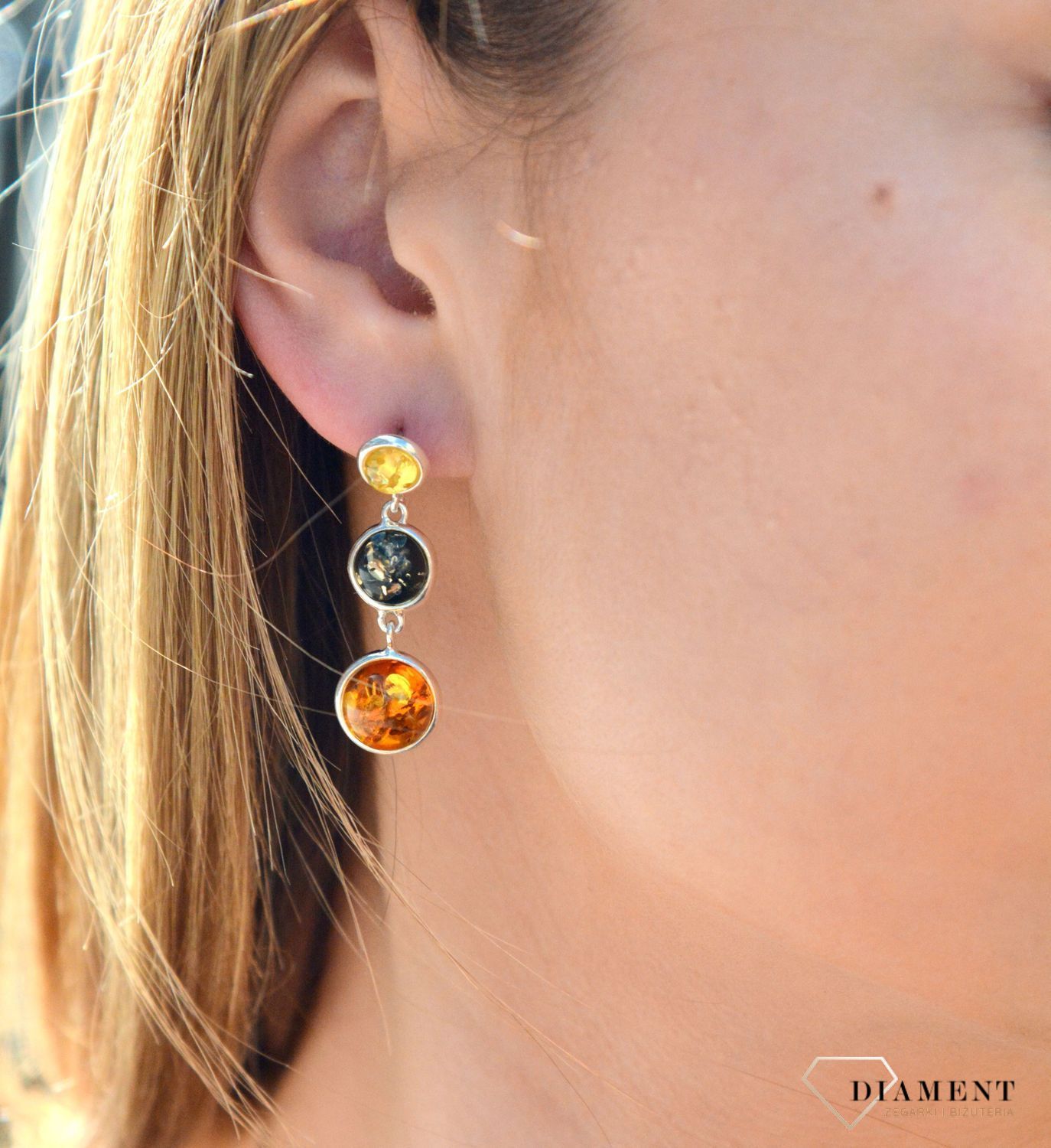 Kolczyki srebrne wiszące z kolorowymi bursztynami DIA-KLC-7096-925. Charakteryzują się stylem klasycznym i zapięciem na wygodny sztyft. Oprawa elementu ozdobnego, wykonana ze srebra, ma efektowny kształt. Bursztyn to słoneczny.jpg