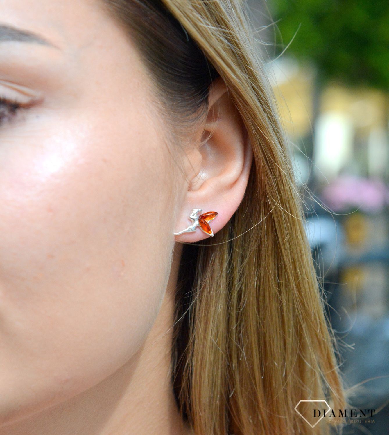 Kolczyki srebrne wkrętki aniołek z bursztynowymi skrzydełkami DIA-KLC-7103-925. Srebrne kolczyki z bursztynem to modelem bardzo ciekawy, ponieważ dzięki ciepłej kolorystyce pięknie podkreśla on urodę. Charakteryzują się stylem.jpg