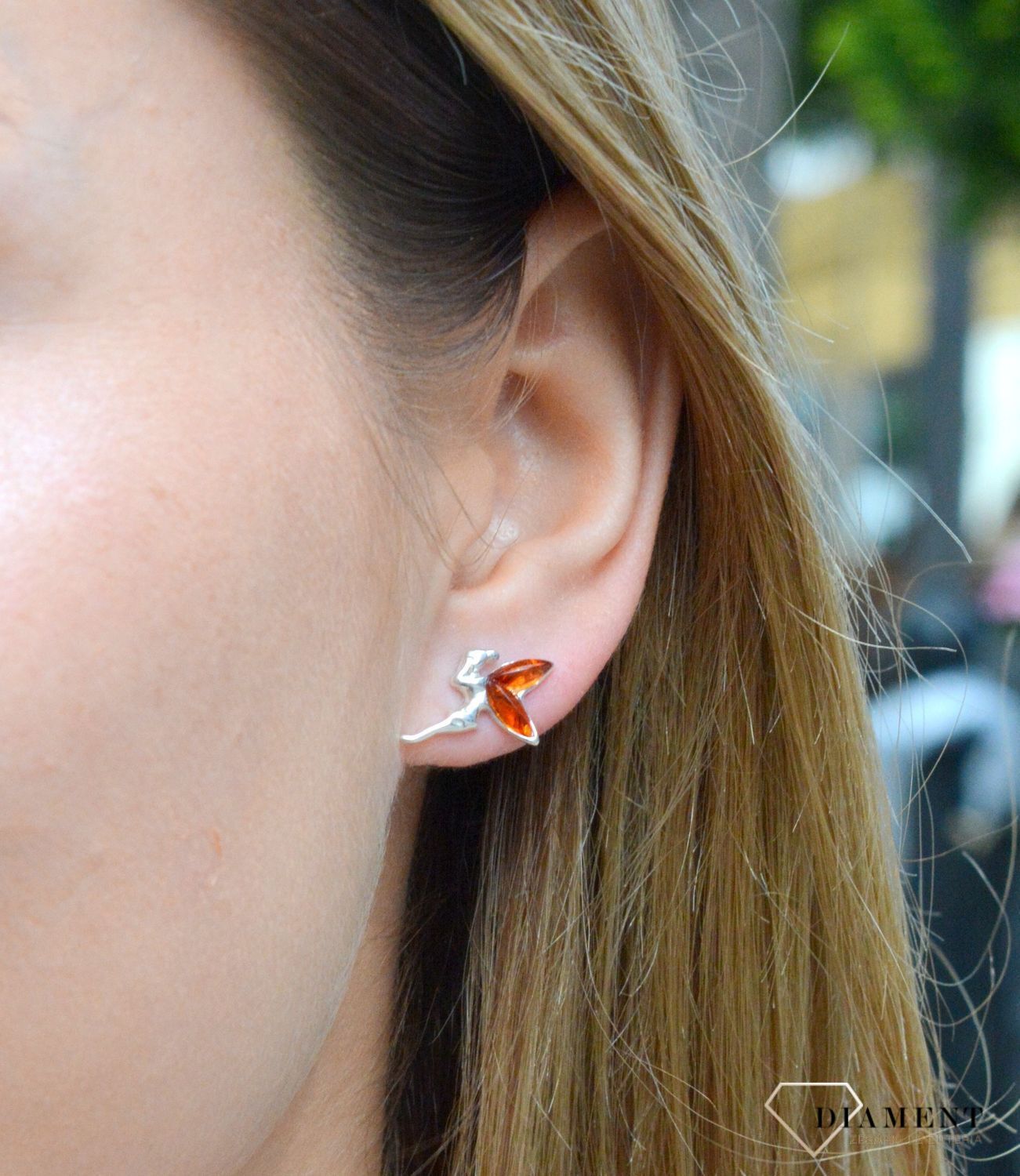 Kolczyki srebrne wkrętki aniołek z bursztynowymi skrzydełkami DIA-KLC-7103-925. Srebrne kolczyki z bursztynem to modelem bardzo ciekawy, ponieważ dzięki ciepłej kolorystyce pięknie podkreśla on urodę. Charakteryzują się stylem.jpg