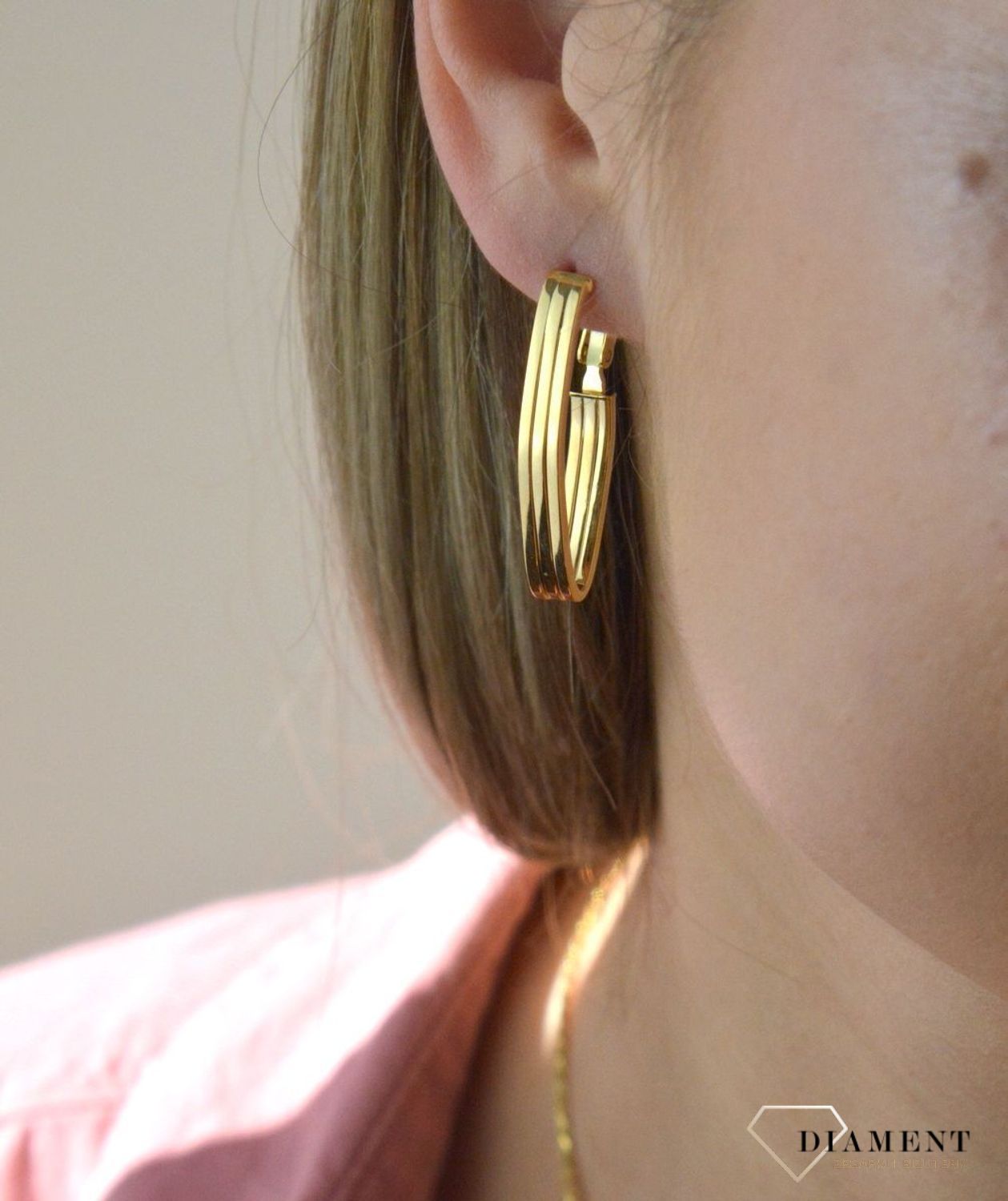 Efektowne złote kolczyki to jeden z ulubionych współczesnych motywów jubilerskich. Biżuteria, która przyciąga wzrok i zachwyca jakością wykonania. Kolczyki składają się z geometrycznego kształtu.jpg