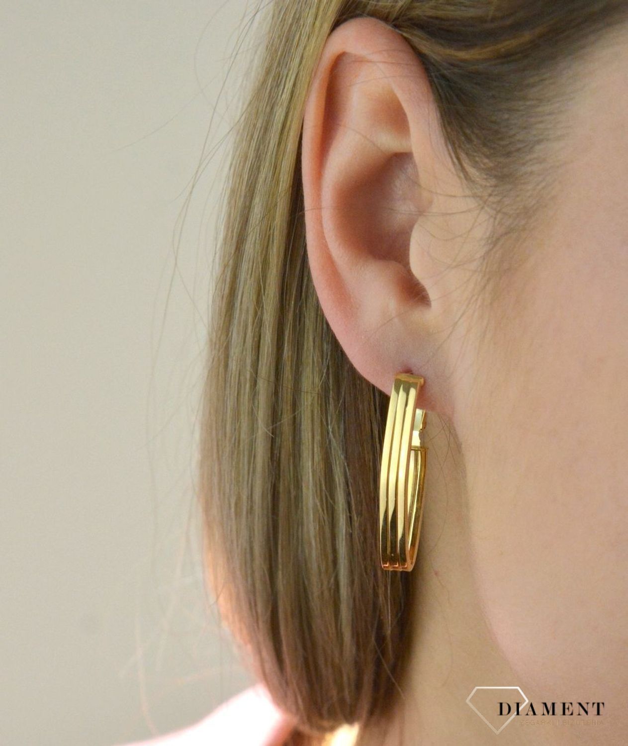 Efektowne złote kolczyki to jeden z ulubionych współczesnych motywów jubilerskich. Biżuteria, która przyciąga wzrok i zachwyca jakością wykonania. Kolczyki składają się z geometrycznego kształtu.jpg