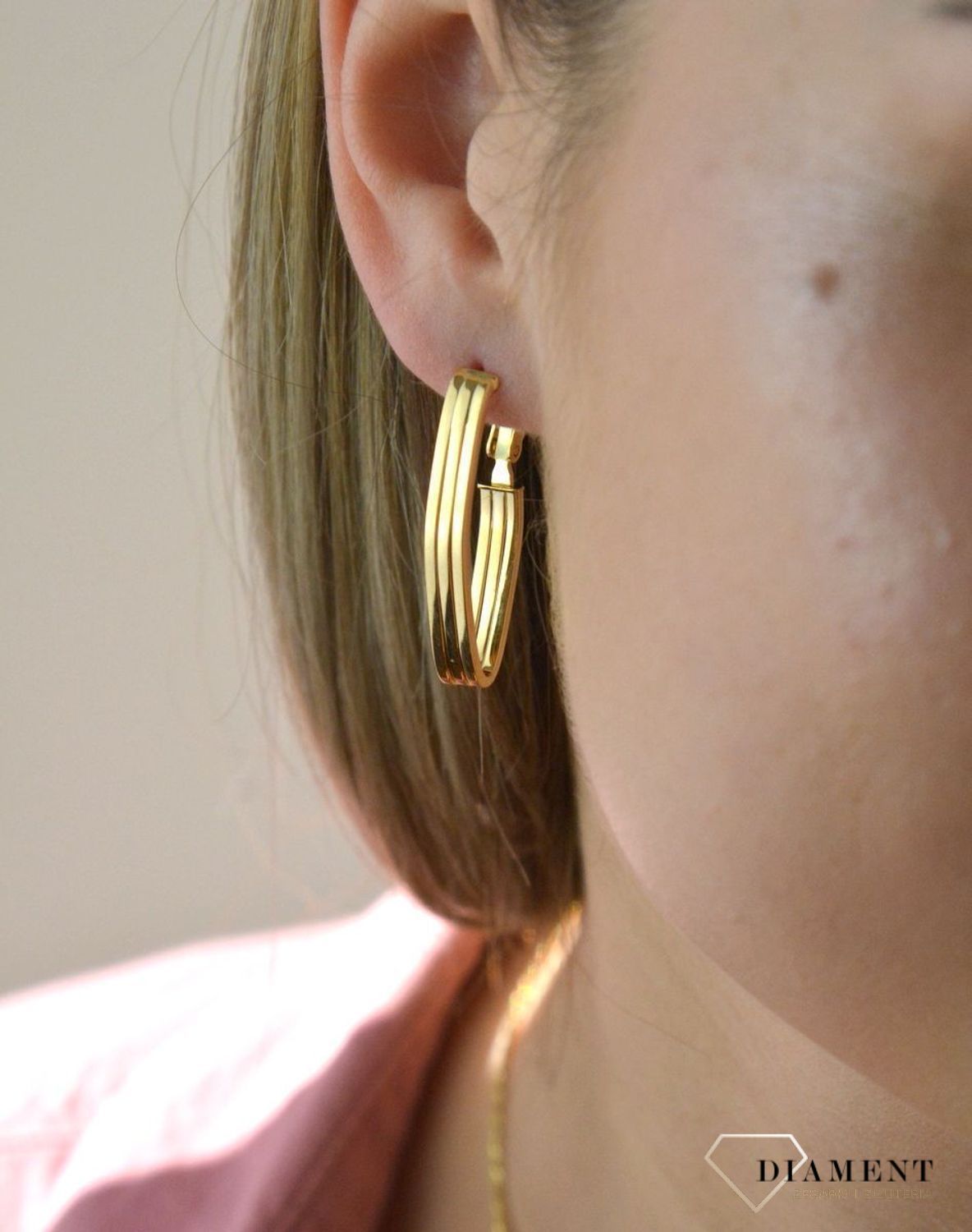 Efektowne złote kolczyki to jeden z ulubionych współczesnych motywów jubilerskich. Biżuteria, która przyciąga wzrok i zachwyca jakością wykonania. Kolczyki składają się z geometrycznego kształtu.jpg