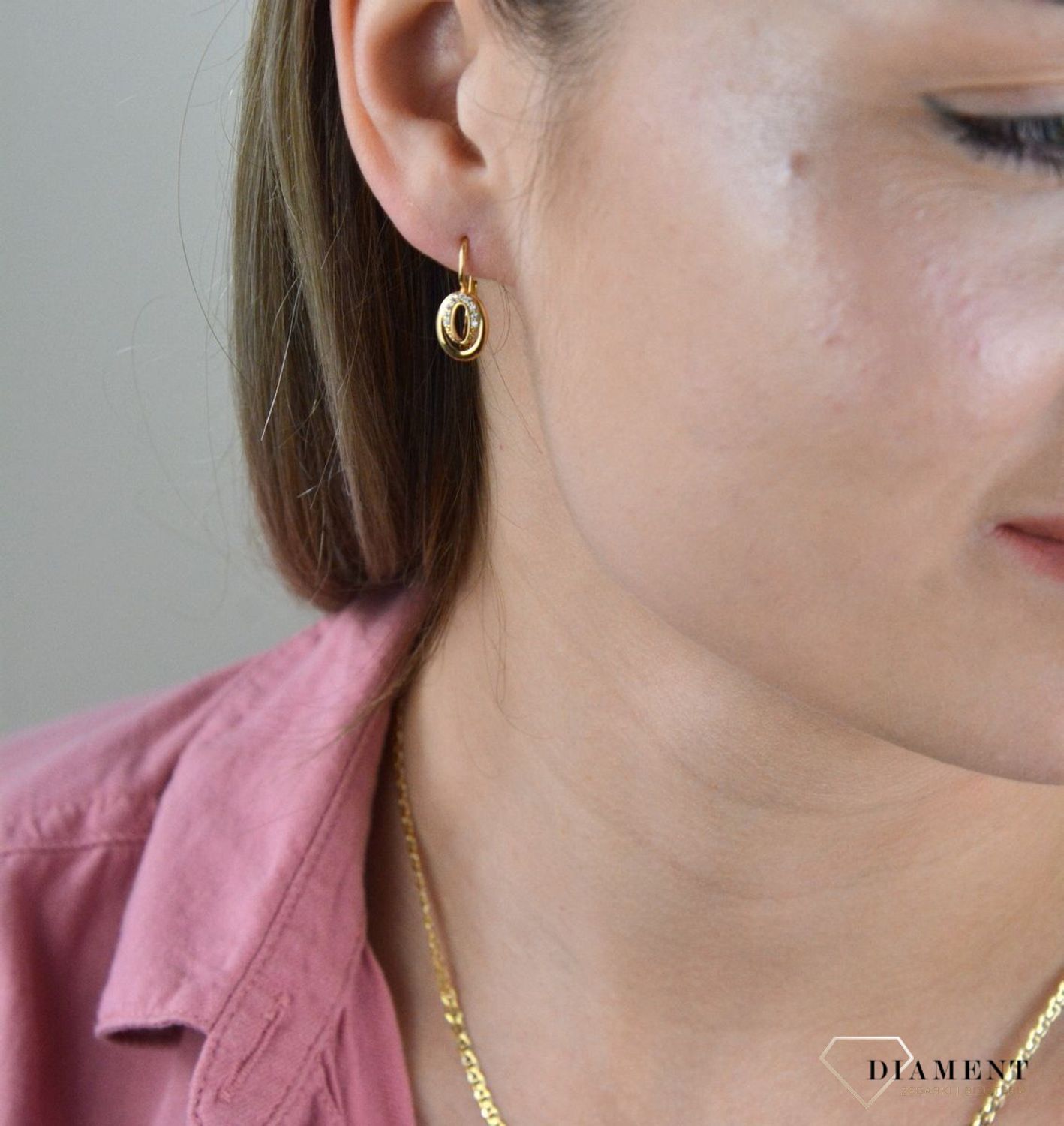 Złote kolczyki 375 wiszące owalne z cyrkoniami DIA-KLC-7764-375. Kolczyki w minimalistycznym stylu, wpisujące się w obecne trendy modowe. Delikatna forma, najwyższej jakości złota to idealne uzupełnienie eleganckich stylizacji.jpg