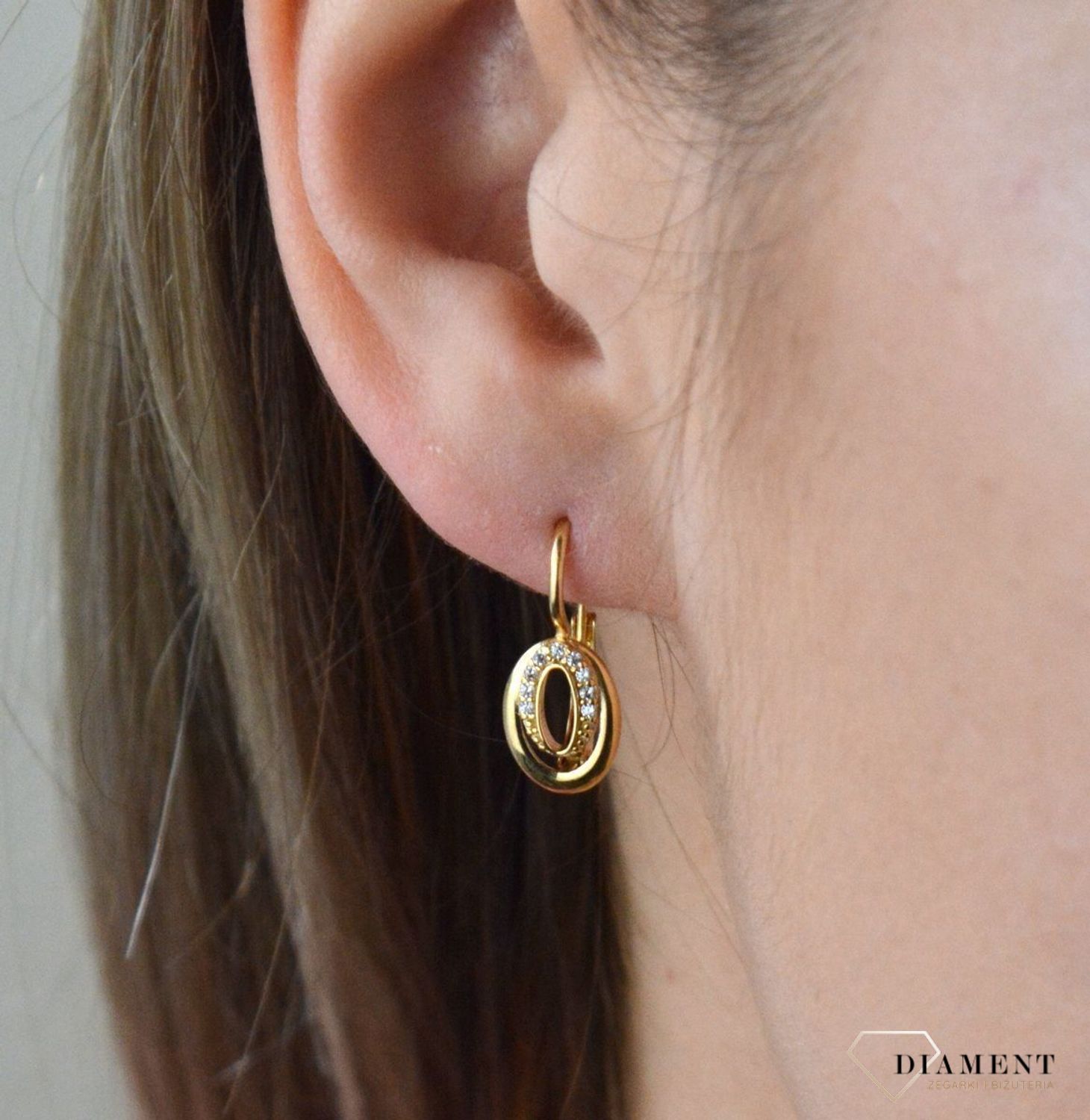 Złote kolczyki 375 wiszące owalne z cyrkoniami DIA-KLC-7764-375. Kolczyki w minimalistycznym stylu, wpisujące się w obecne trendy modowe. Delikatna forma, najwyższej jakości złota to idealne uzupełnienie eleganckich stylizacji.jpg