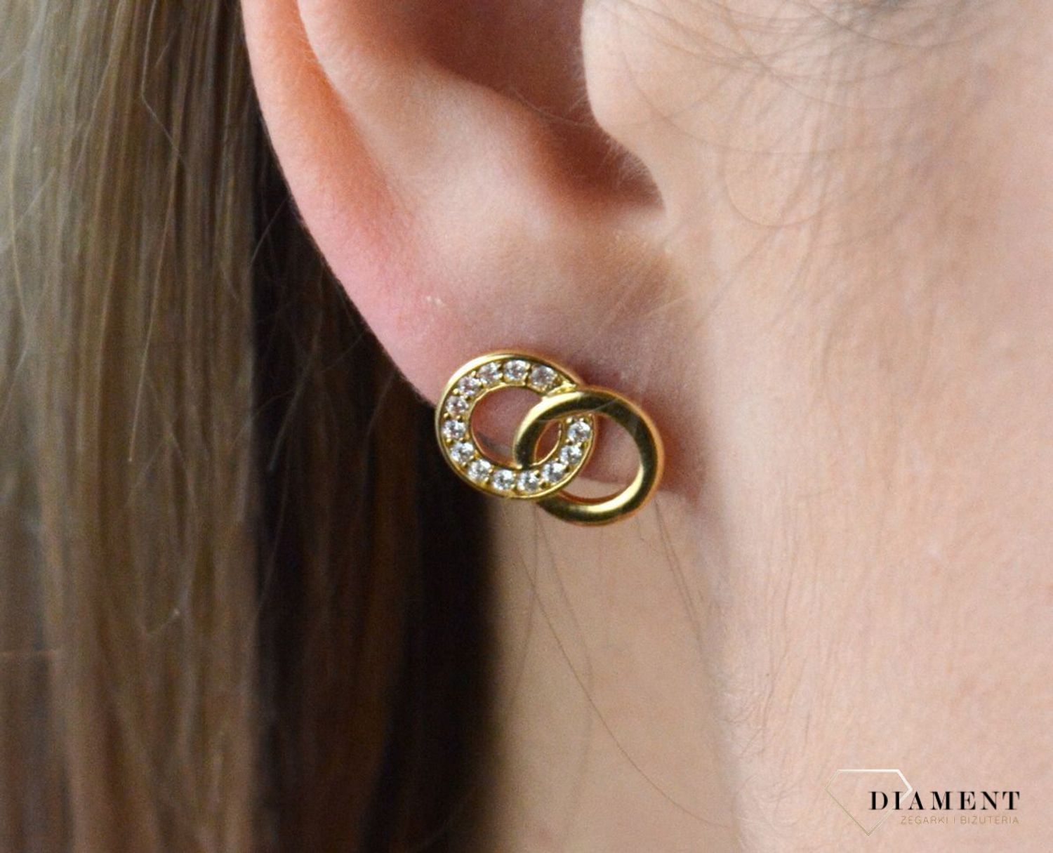 Złote kolczyki 375 połączone kółka z cyrkoniami. Kolczyki pięknie sprawdzą się jako prezent i staną się pamiątką na długie lata. Kolczyki zostały wykonane z złota próba 375. Szerokość kolczyków wynosi 1,3 cm..jpg