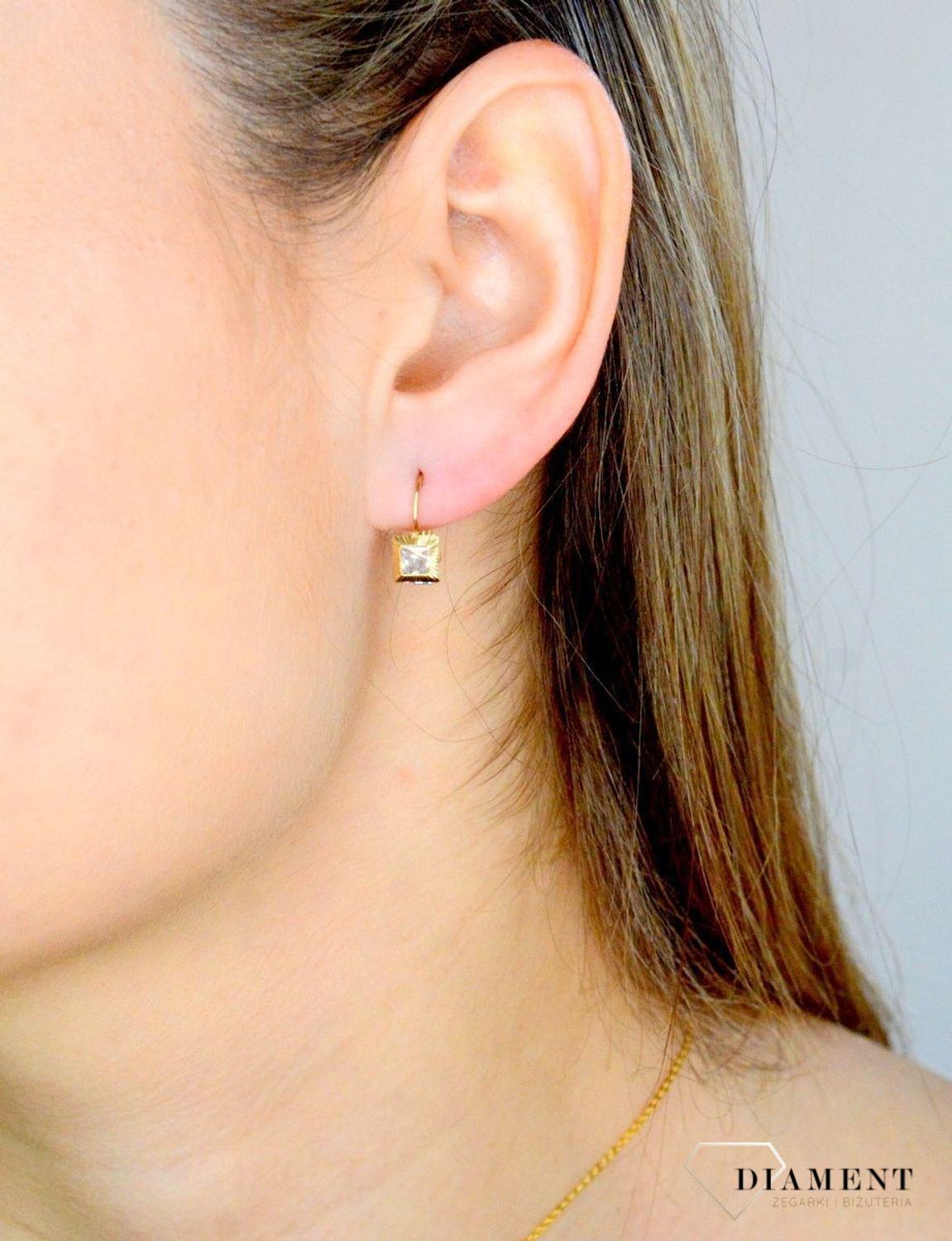 Złote kolczyki 333 wiszące kwadraciki z cyrkonią DIA-KLC-9059-333. Kolczyki zostały wykonane z najwyższej jakości 14-karatowego żółtego złota, próba 333. Kolczyki posiadają wygodne zapięcie na bigiel..jpg