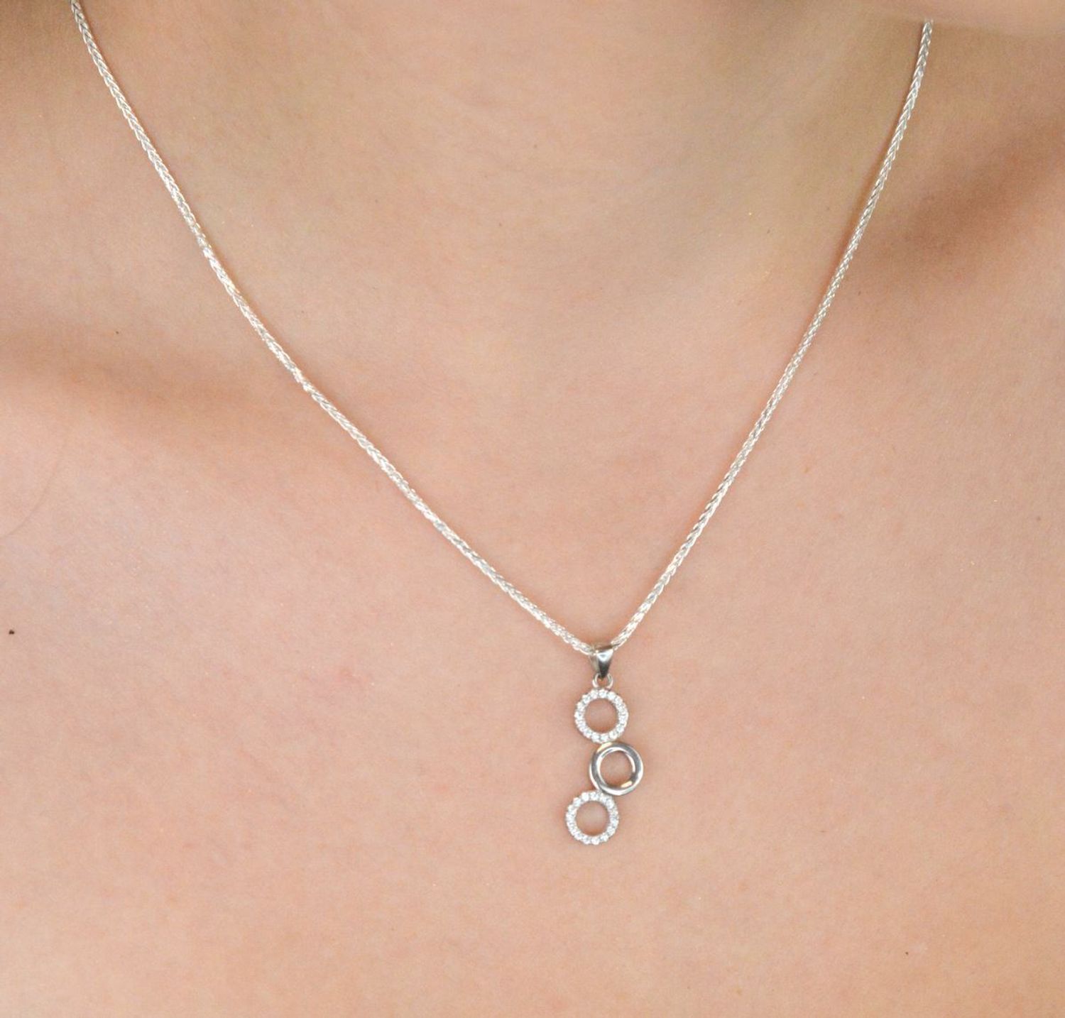 Elegancki srebrny komplet DIA-KPL-11828-925 z potrójnymi kółeczkami i błyszczącymi cyrkoniami. Kolczyki z wygodnym zapięciem na bigiel. Waga 4,60 g, długość kolczyków 3,8 cm, zawieszka 2,2 cm.3.jpg