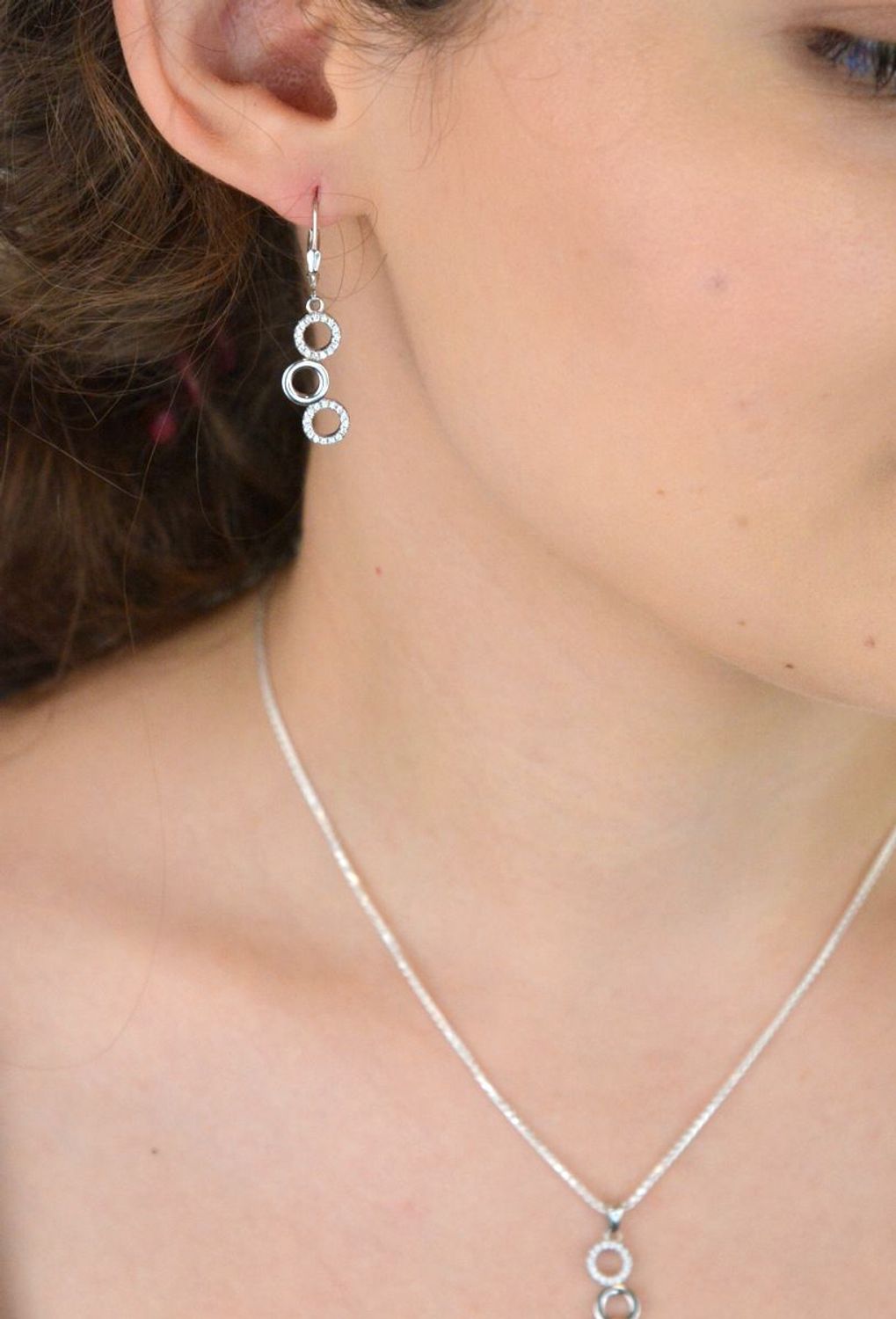 Elegancki srebrny komplet DIA-KPL-11828-925 z potrójnymi kółeczkami i błyszczącymi cyrkoniami. Kolczyki z wygodnym zapięciem na bigiel. Waga 4,60 g, długość kolczyków 3,8 cm, zawieszka 2,2 cm.3.jpg