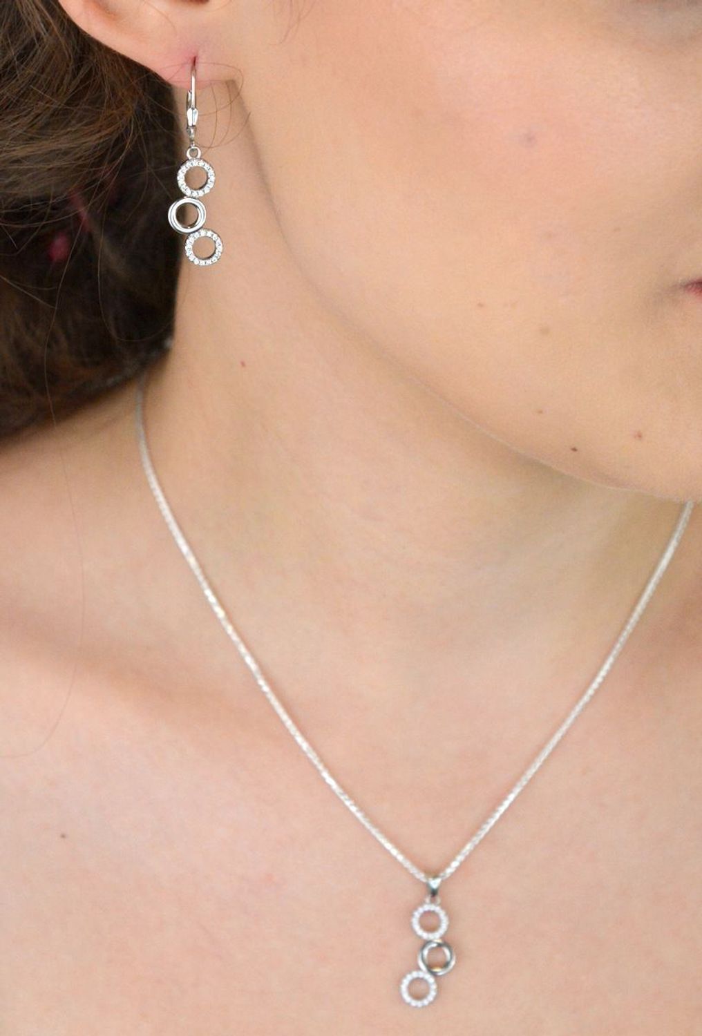 Elegancki srebrny komplet DIA-KPL-11828-925 z potrójnymi kółeczkami i błyszczącymi cyrkoniami. Kolczyki z wygodnym zapięciem na bigiel. Waga 4,60 g, długość kolczyków 3,8 cm, zawieszka 2,2 cm.3.jpg