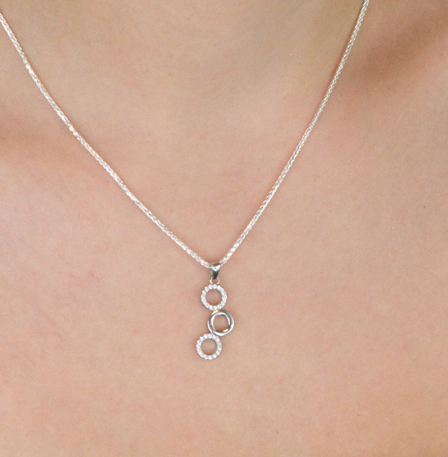 Elegancki srebrny komplet DIA-KPL-11828-925 z potrójnymi kółeczkami i błyszczącymi cyrkoniami. Kolczyki z wygodnym zapięciem na bigiel. Waga 4,60 g, długość kolczyków 3,8 cm, zawieszka 2,2 cm.3.jpg