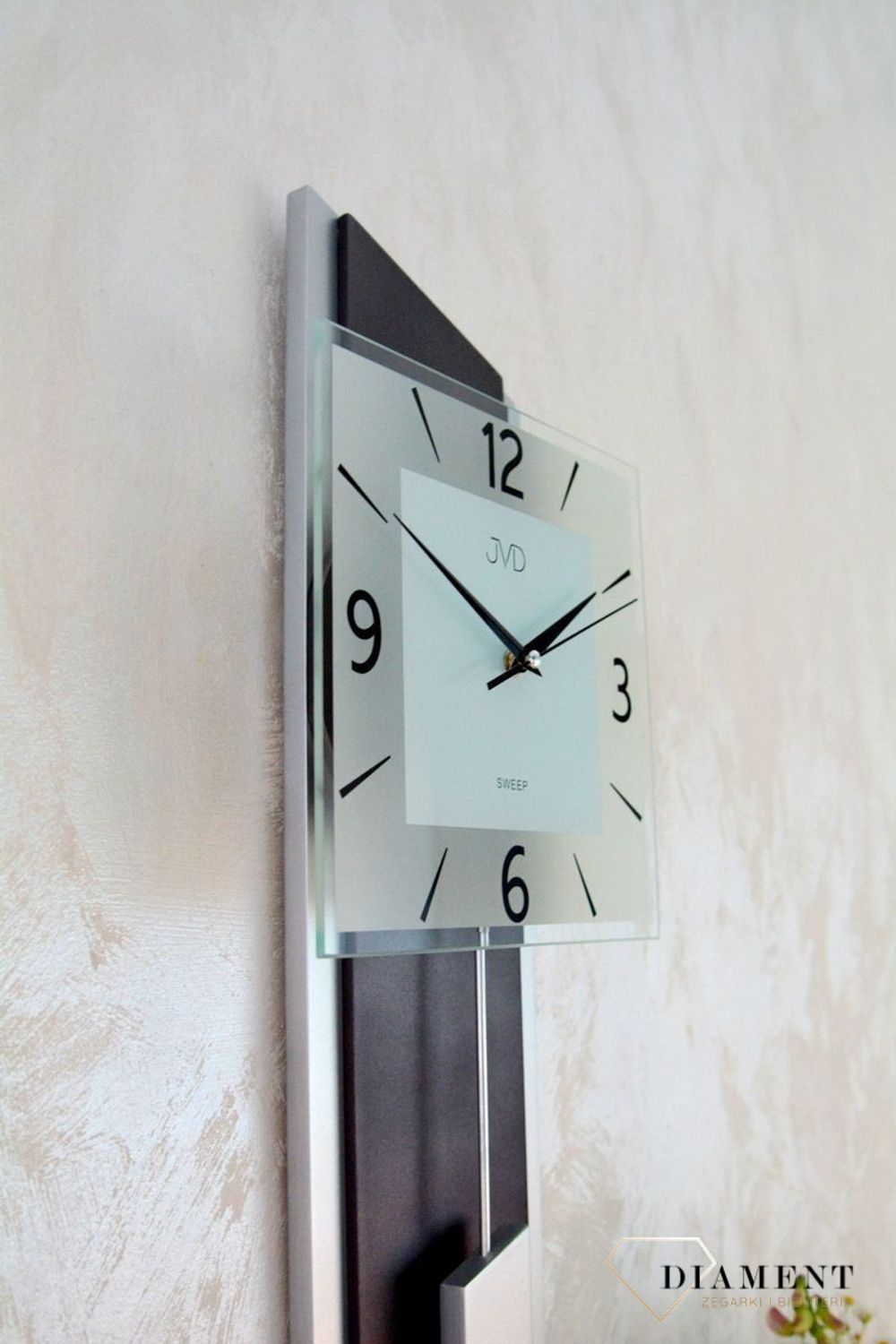 Zegar ścienny wahadłowy JVD NS19052.2 wyposażony jest w kwarcowy mechanizm, zasilany za pomocą baterii. Posiada bardzo wysoką dokładność mierzenia czasu +- 10 sekund w przeciągu 30 dni.jpg