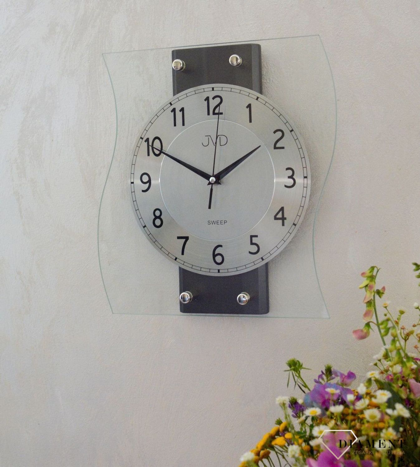 Ścienny zegar JVD NS21053.2 wyposażony jest w kwarcowy mechanizm, zasilany za pomocą baterii. Posiada bardzo wysoką dokładność mierzenia czasu +- 10 sekund w przeciągu 30 dni..jpg