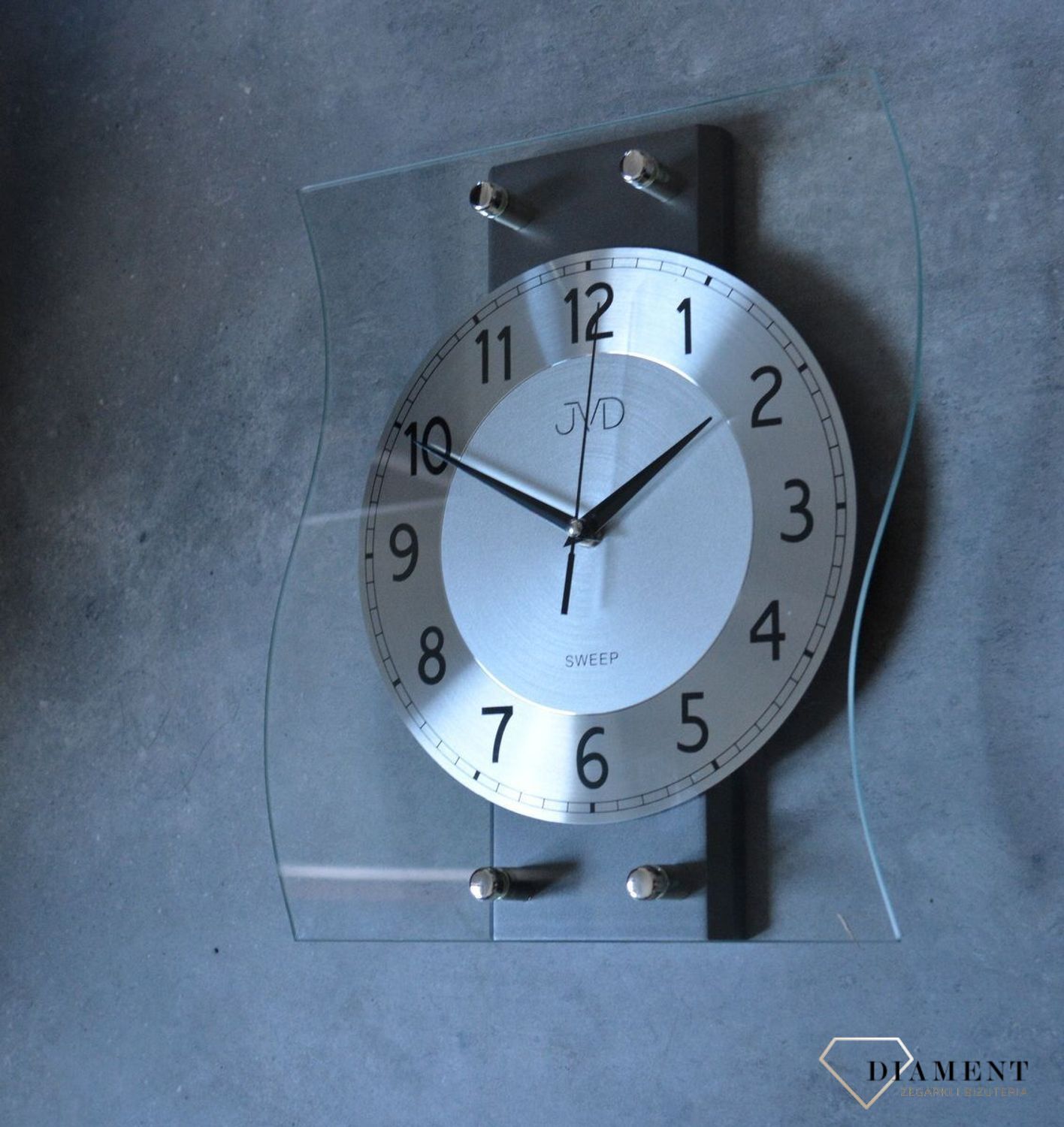 Ścienny zegar JVD NS21053.2 wyposażony jest w kwarcowy mechanizm, zasilany za pomocą baterii. Posiada bardzo wysoką dokładność mierzenia czasu +- 10 sekund w przeciągu 30 dni..jpg