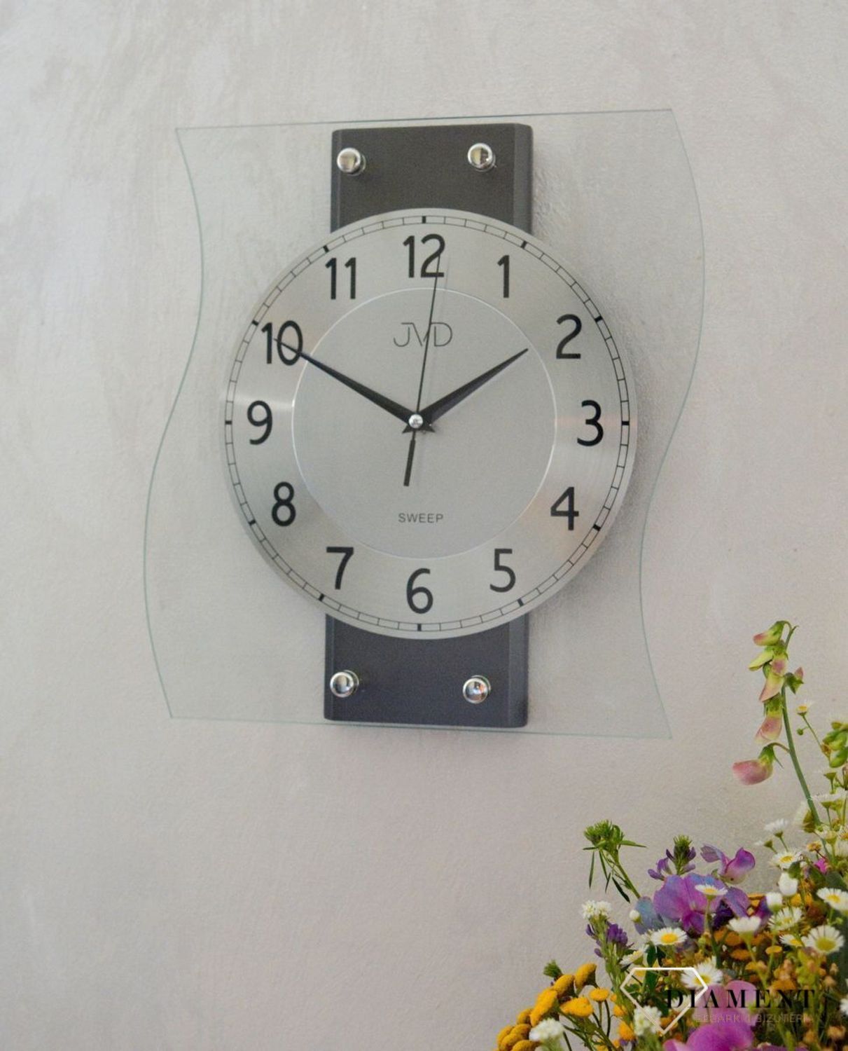 Ścienny zegar JVD NS21053.2 wyposażony jest w kwarcowy mechanizm, zasilany za pomocą baterii. Posiada bardzo wysoką dokładność mierzenia czasu +- 10 sekund w przeciągu 30 dni..jpg