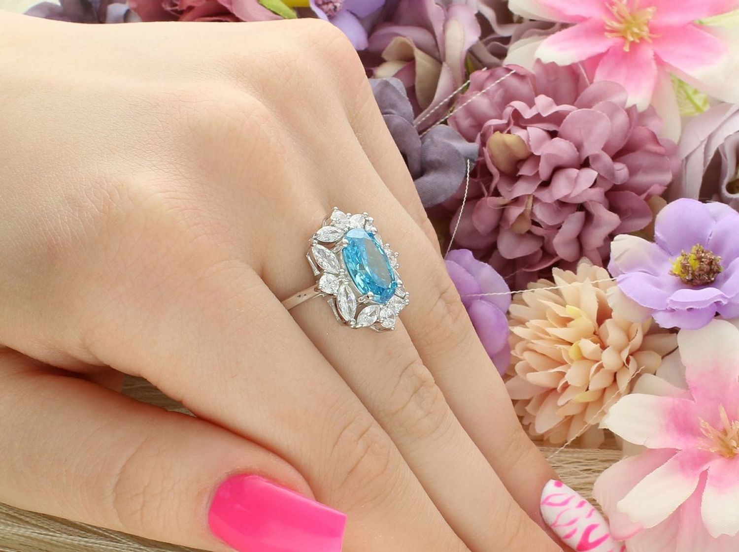 Wyjątkowy srebrny pierścionek z niebieską cyrkonią otoczoną białymi kamieniami. Duży owalny kształt 2,0 × 1,8 cm, waga 6,10 g. Idealny na prezent i eleganckie okazje.1.jpg