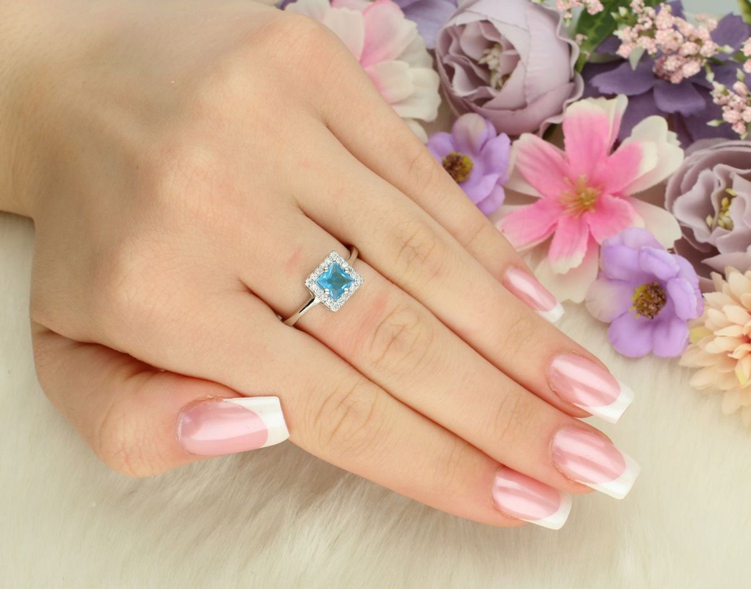 Pierścionek damski srebrny 925 DIA-PRS-13380-925 z błękitną cyrkonią w kwadratowej oprawie i białymi kamieniami. Ozdoba 8 × 8 mm, szyna 3 mm, waga 2,30 g. Elegancki i nowoczesny.1.jpg