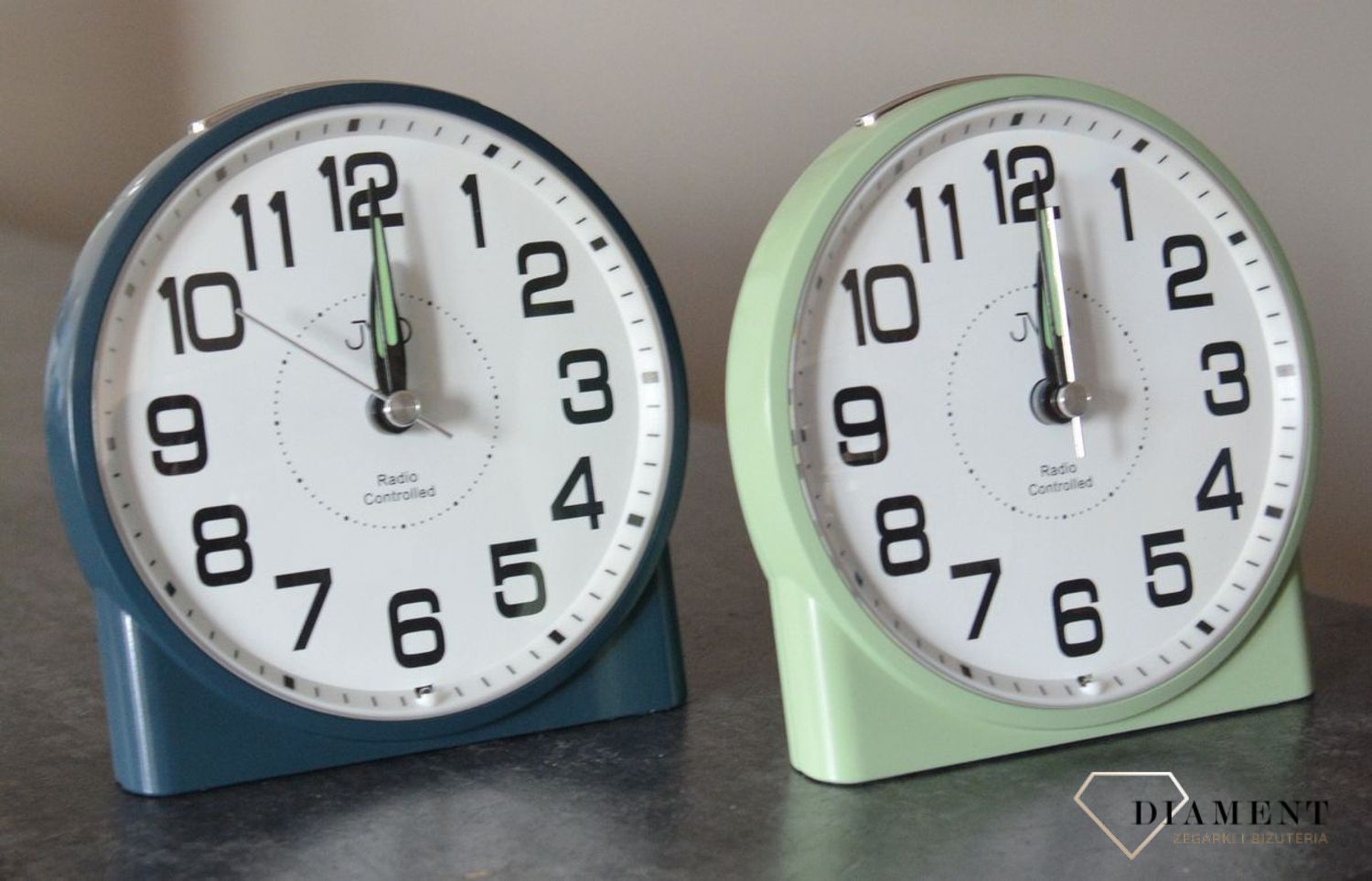 Budzik klasyczny JVD sterowany radiowo zielony RB22.2.  Jest realizowane za pomocą panelu którego aktywacja powoduje świecenie całego wyświetlacza za pomocą przycisku. Podświetlenie jest w kolorze pomarańczo.jpg